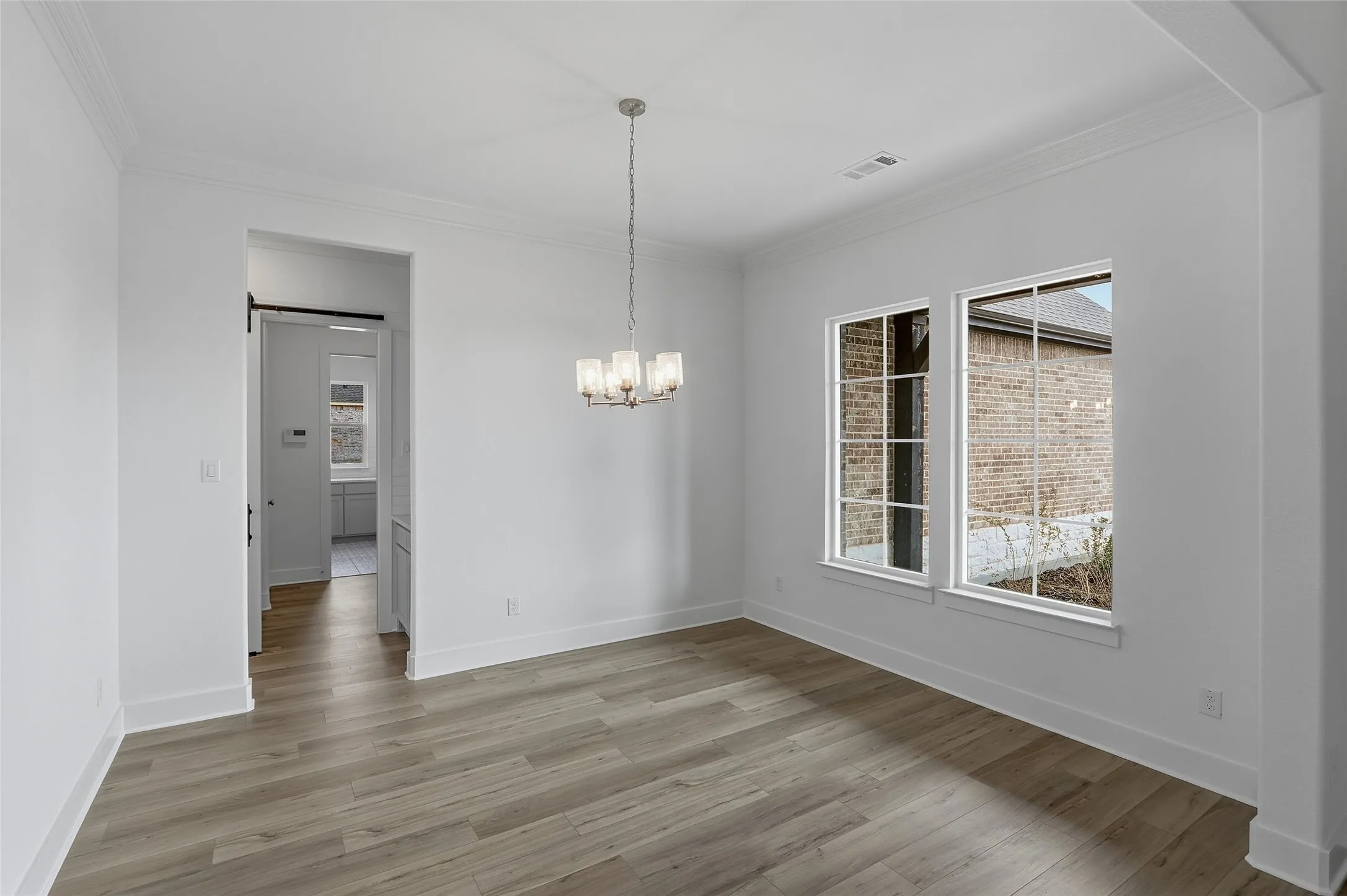 Unfurnished dining area with crown molding, hanging lights, and light wood-type flooring