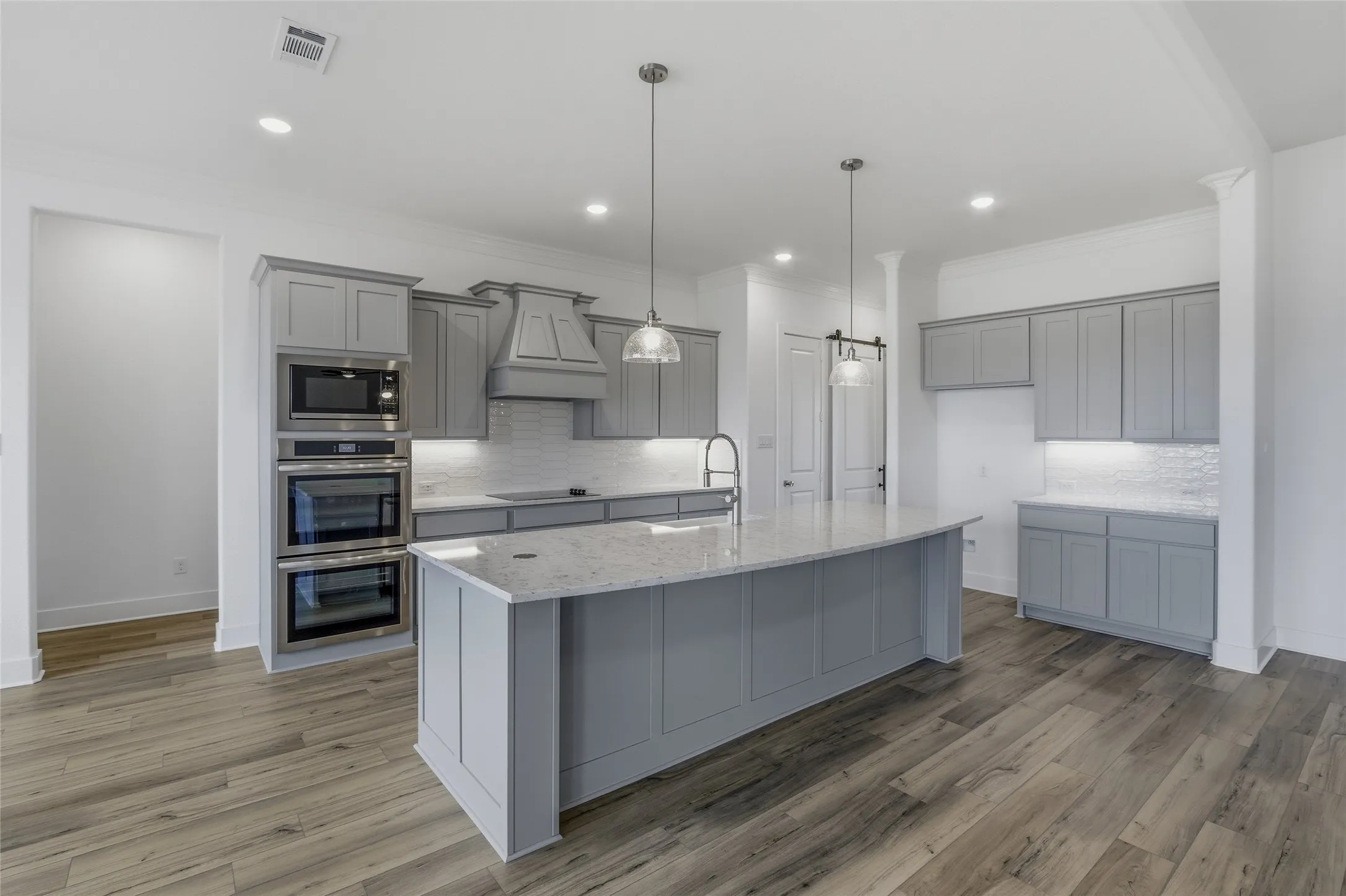 Kitchen with gray cabinetry, stainless steel appliances, pendant lighting, tasteful backsplash, and ornamental molding