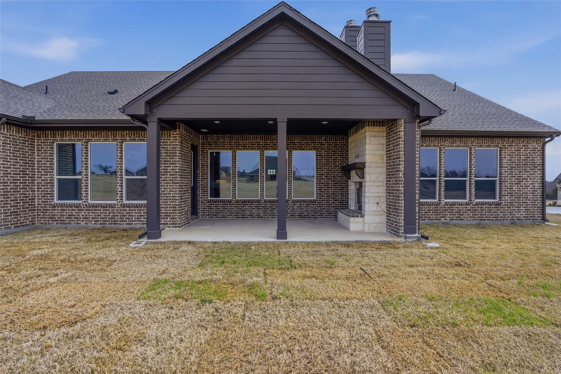Back of property featuring a patio area, a lawn, and brick siding