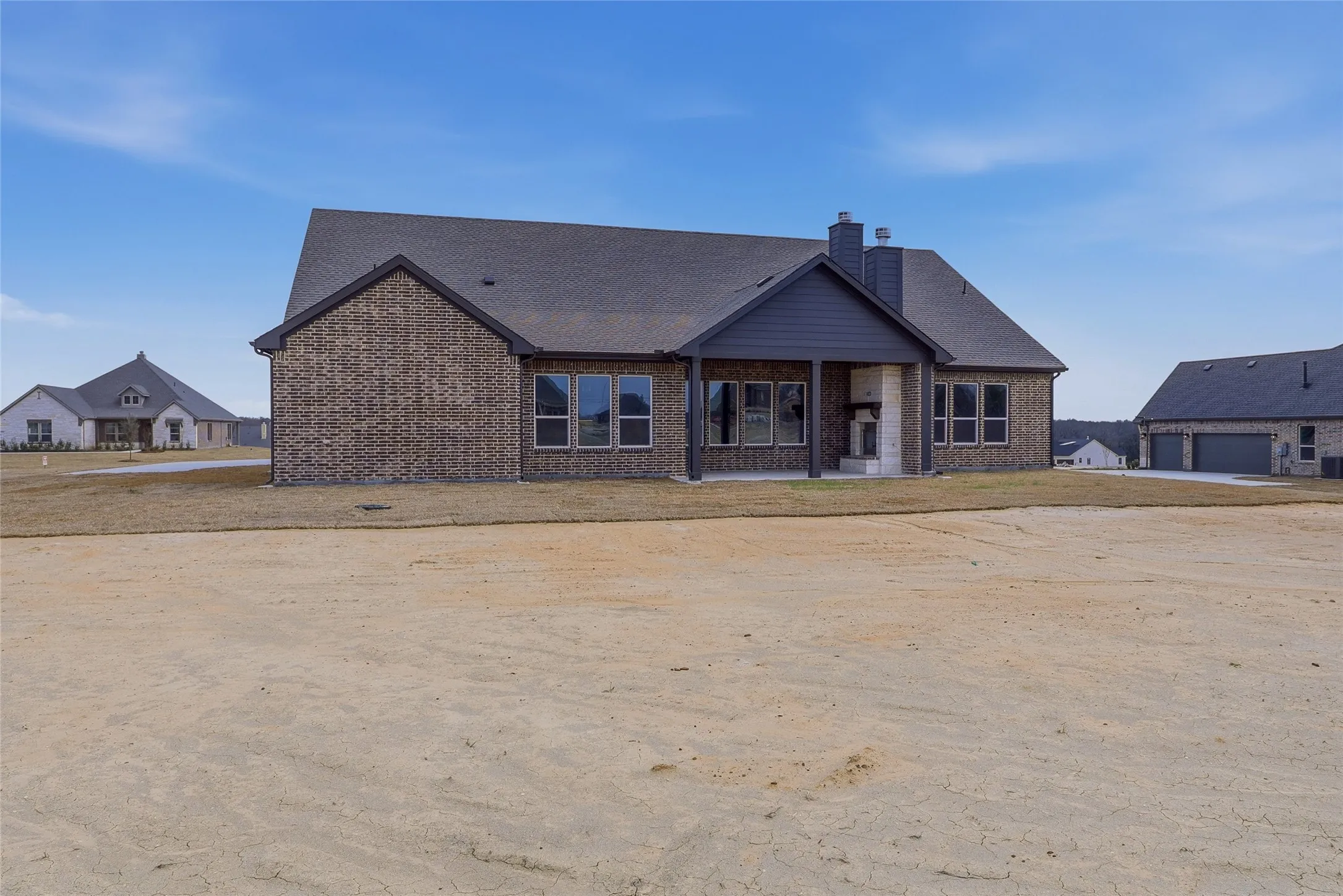 Rear view of property with a chimney, brick siding, and a patio area