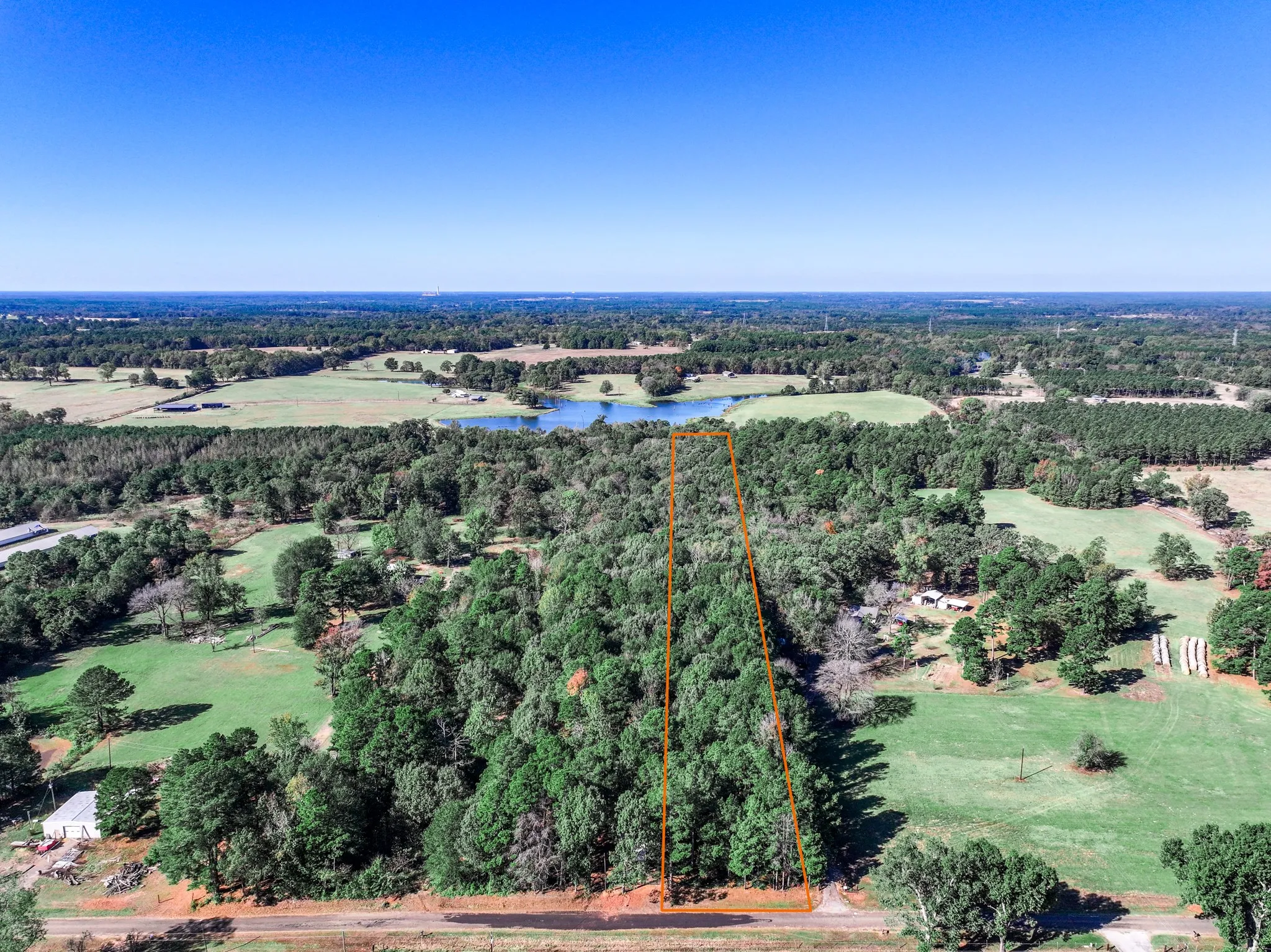 Aerial view of property and surrounding area with a nearby body of water and property parcel outlined