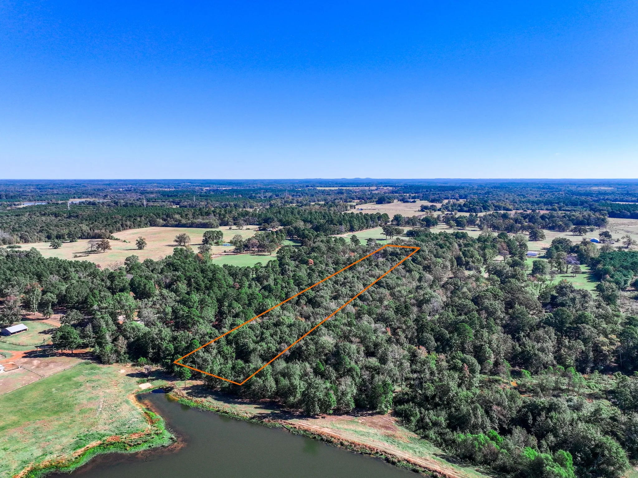 Aerial view of property's location with a nearby body of water and property parcel outlined