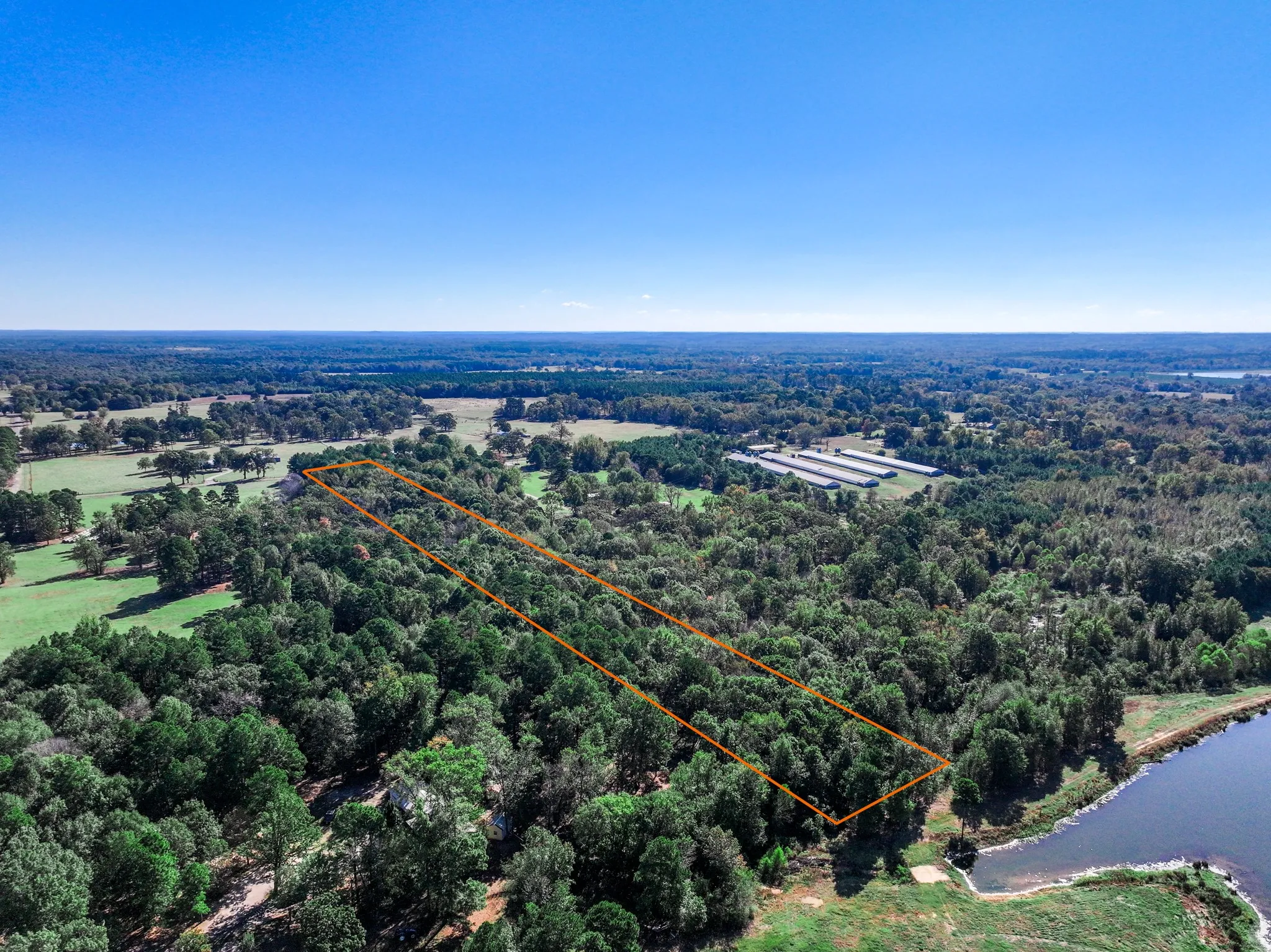 Aerial view of property and surrounding area featuring property boundaries highlighted and a large body of water