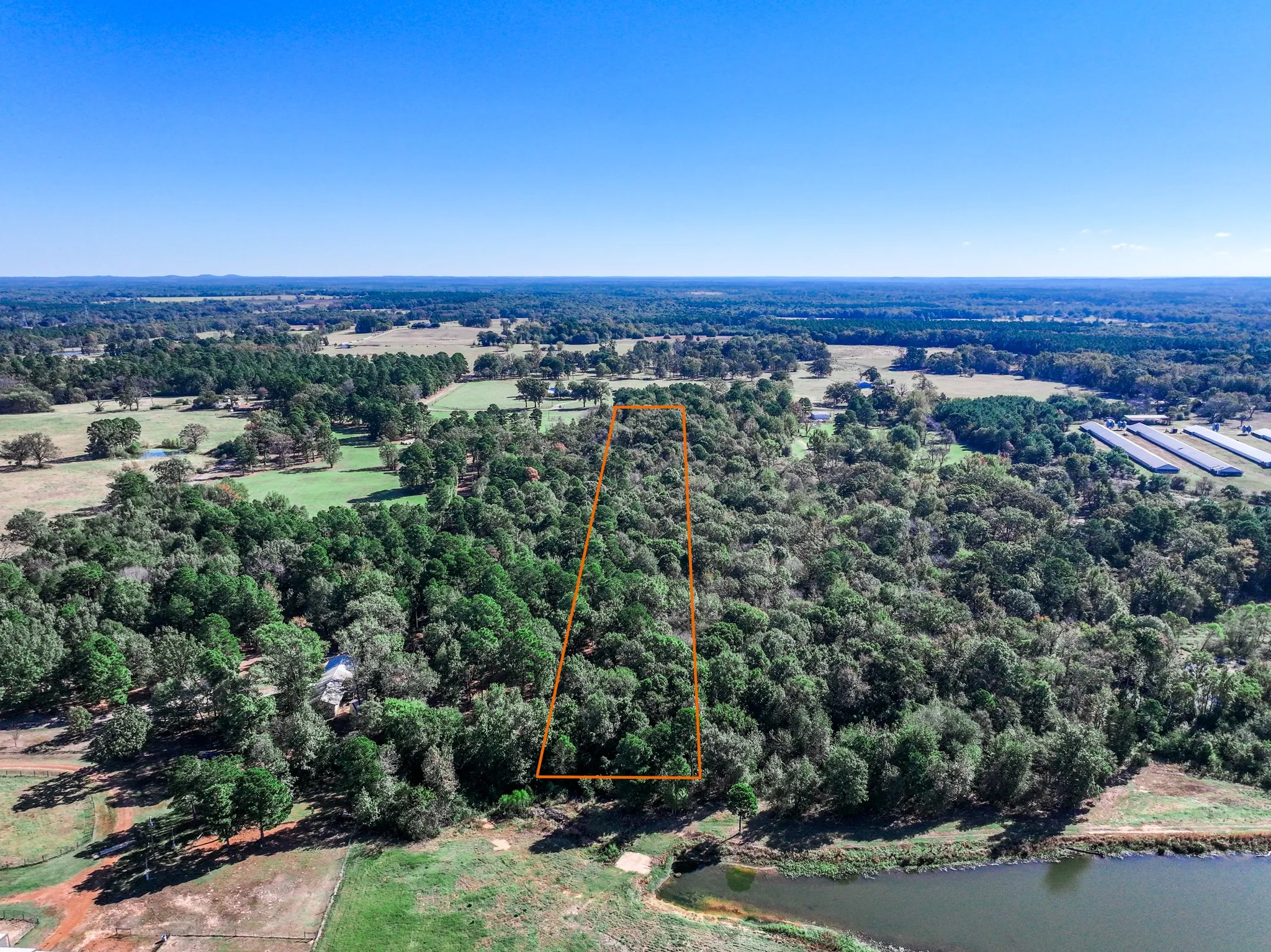 Aerial view of property's location featuring a heavily wooded area and property parcel outlined