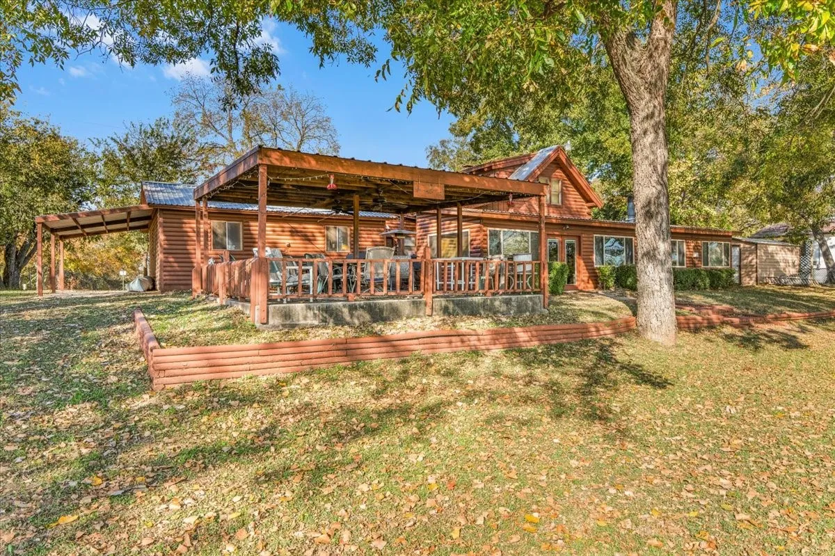 Back of property with a lawn, a wooden deck, a metal roof, and an attached carport