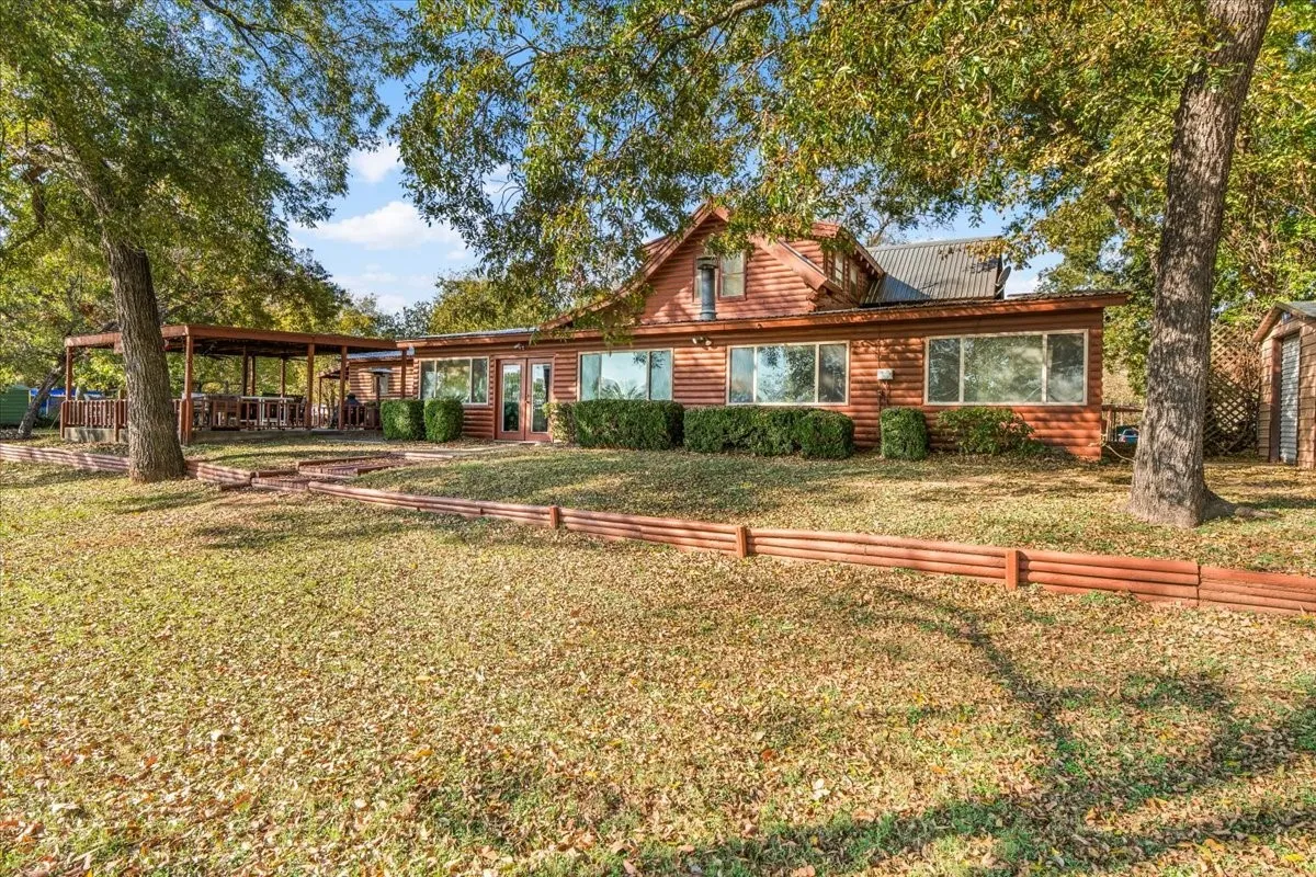 View of back of home with log veneer siding and a front yard