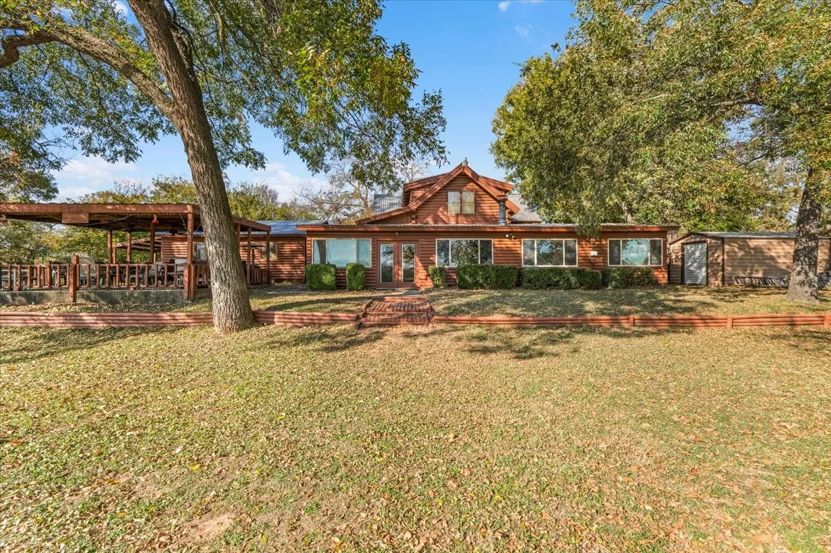 View of back of property with a front yard and a shed