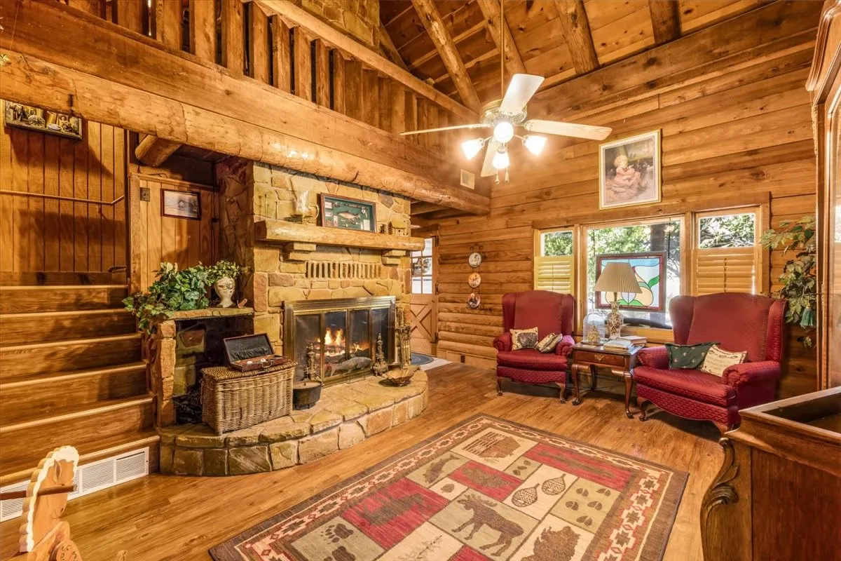 Living room featuring wood finished floors, high vaulted ceiling, stairs, a wood ceiling with exposed beams, and ceiling fan and virtual fire in fireplace