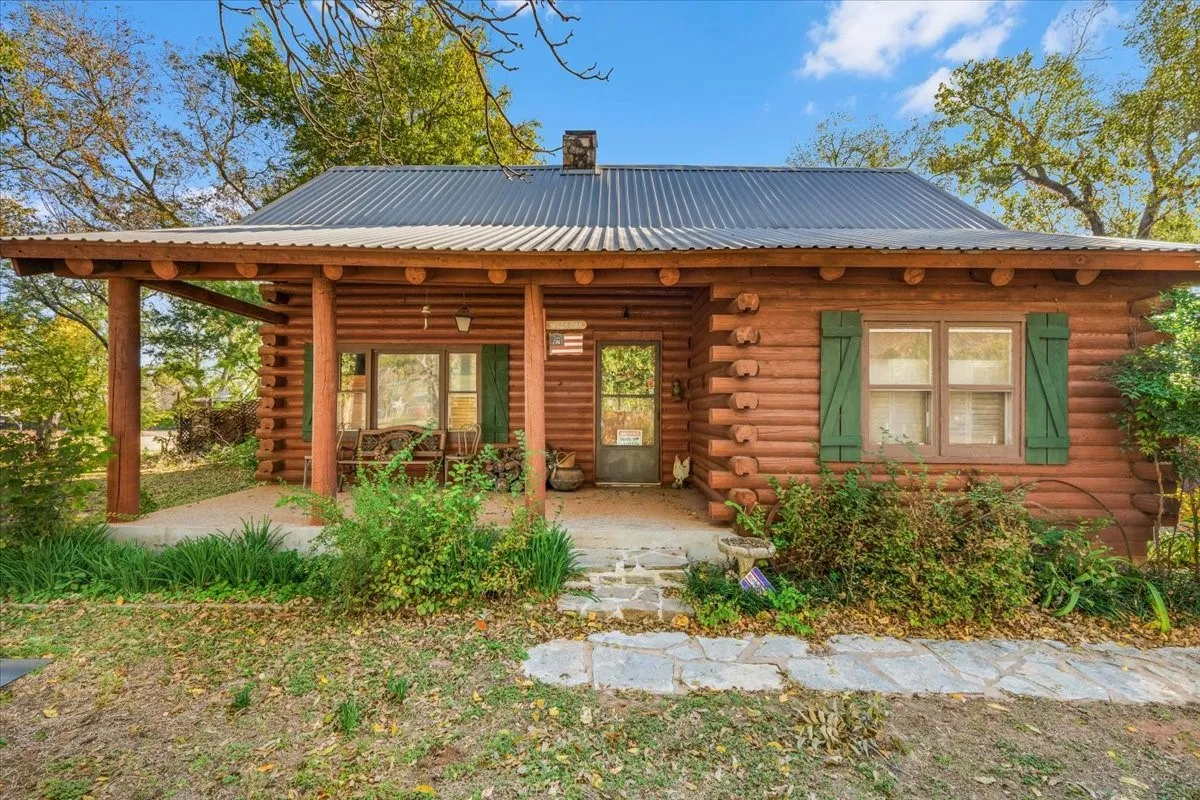 Front of property featuring log siding, covered porch, and a metal roof