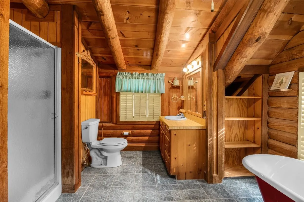 Full bath featuring wooden walls, a stall shower, a wooden ceiling with exposed beams, a soaking tub, and vanity