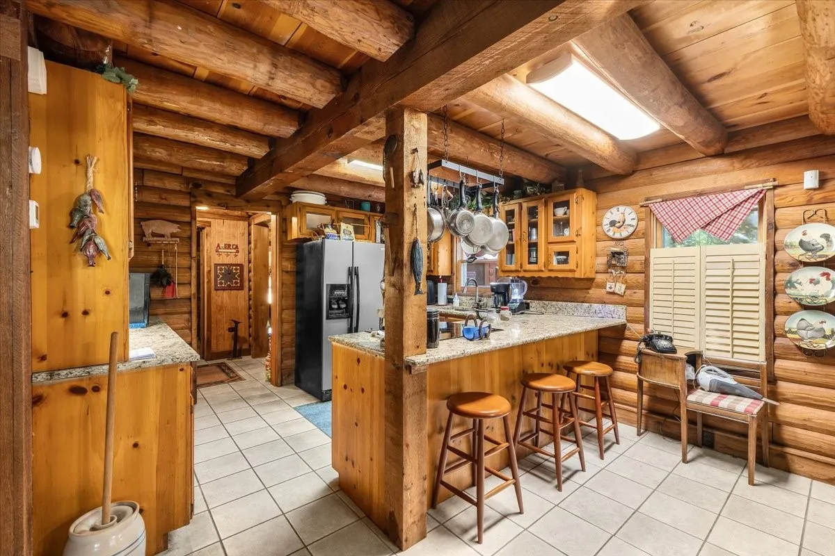 Kitchen featuring rustic walls, glass insert cabinets, a breakfast bar, stainless steel fridge, and light tile patterned flooring