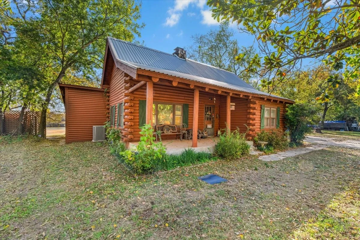 Front view of property with a metal roof, log exterior, a chimney, and a porch