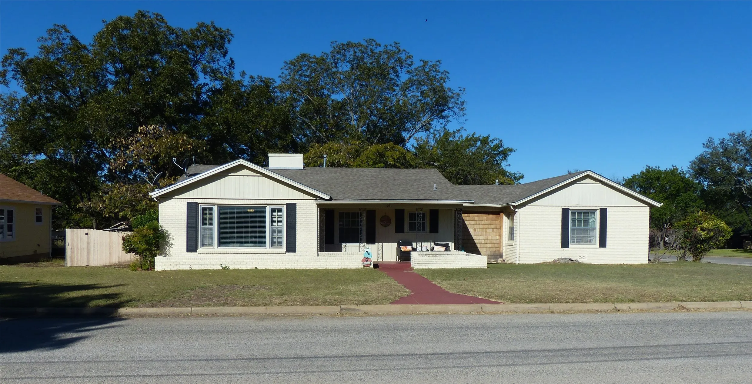 Single story home featuring a porch, brick siding, a front yard, and a chimney