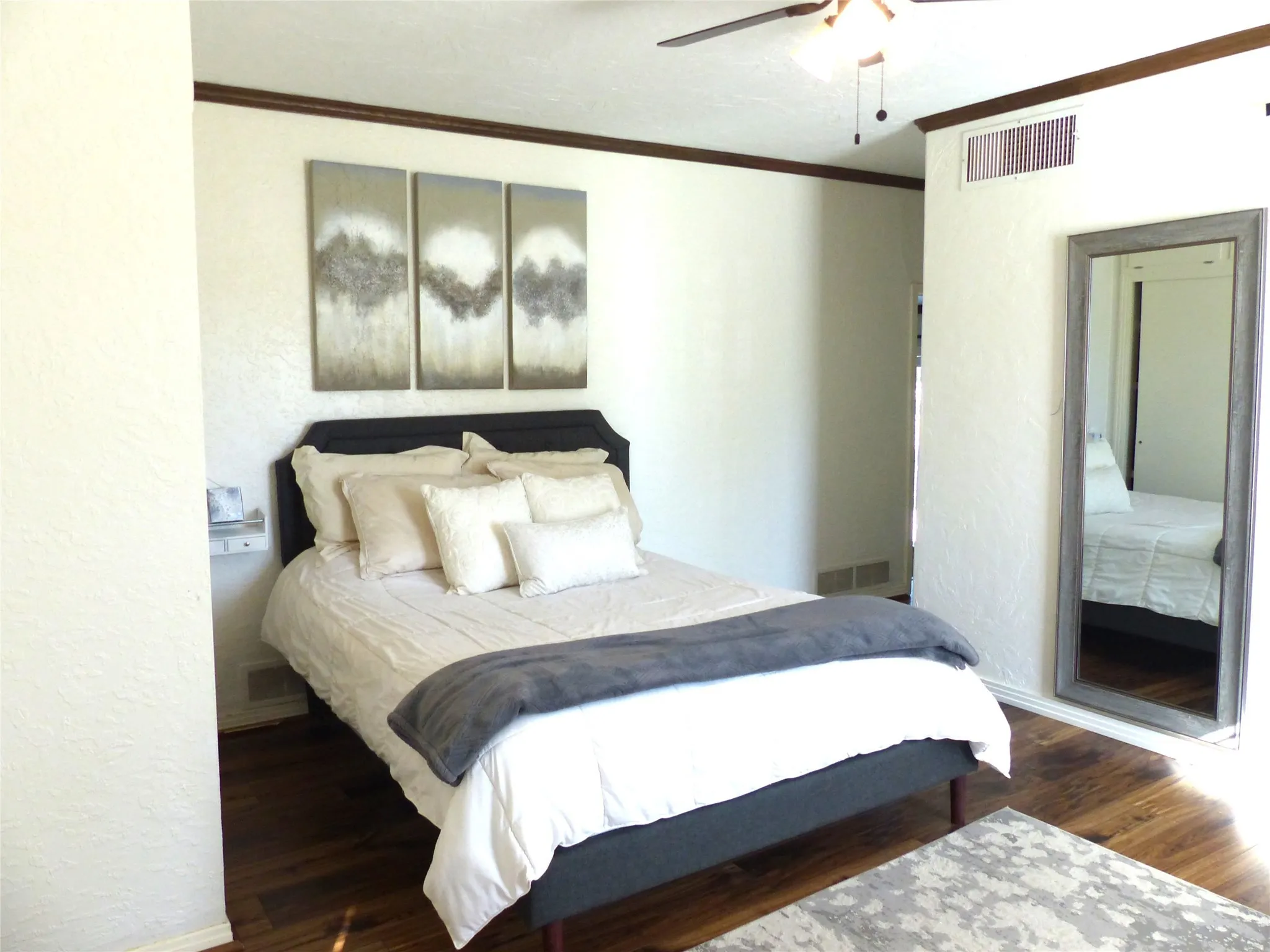 Bedroom with ornamental molding, a textured wall, wood finished floors, and a ceiling fan
