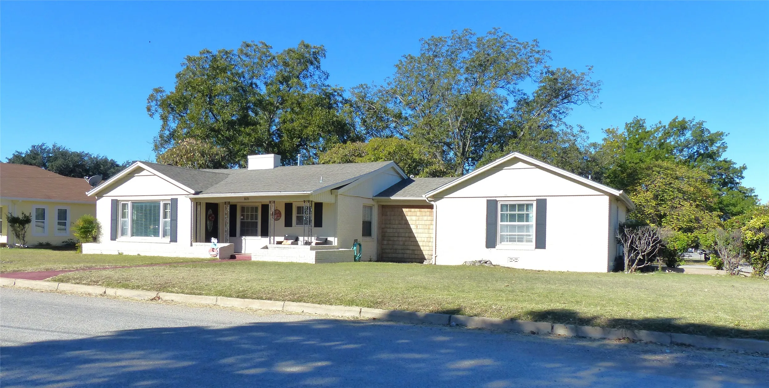 Single story home with a porch, a front yard, a chimney, outdoor lounge area, and a shingled roof