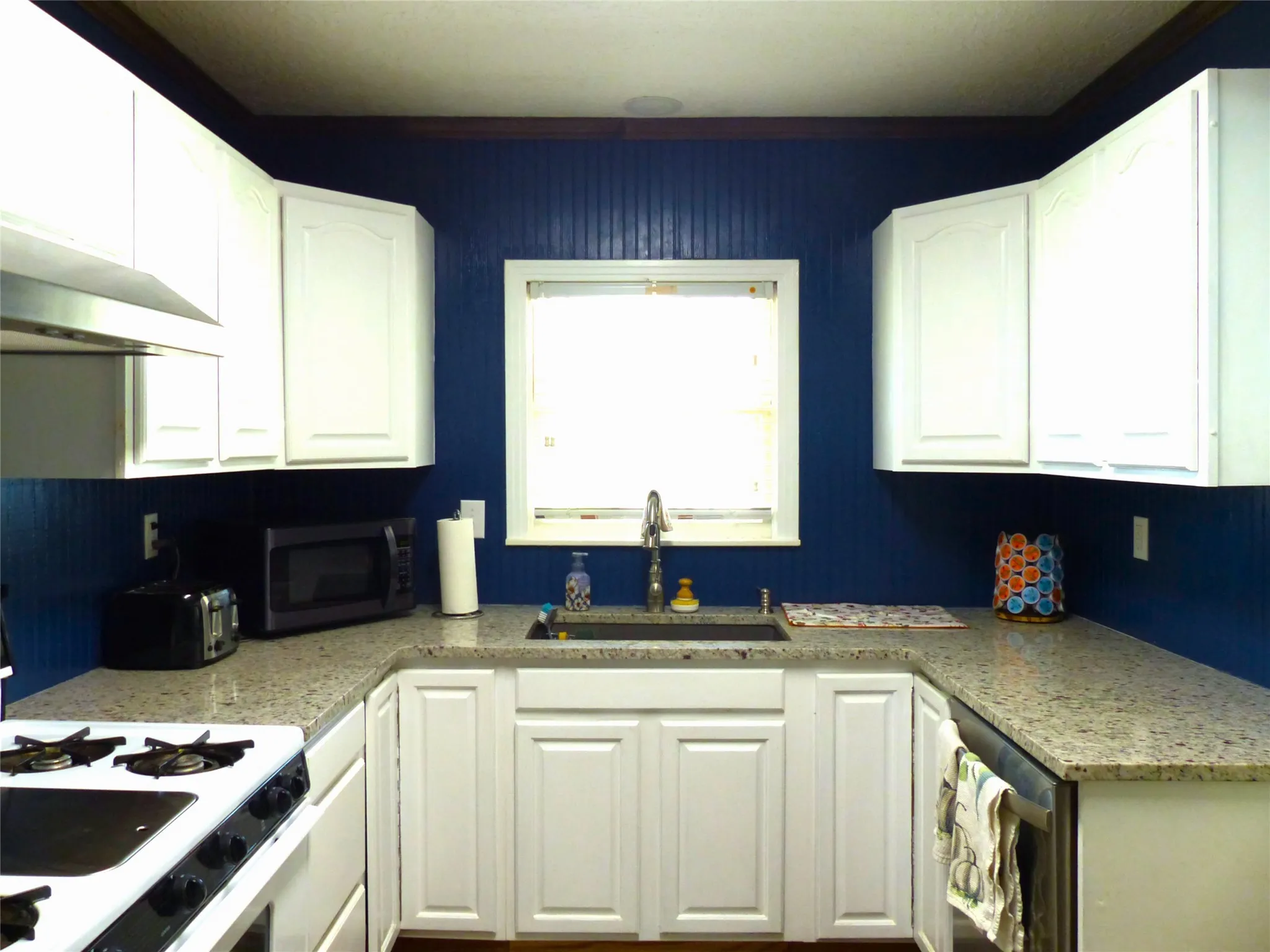 Kitchen featuring white range with gas cooktop and white cabinets