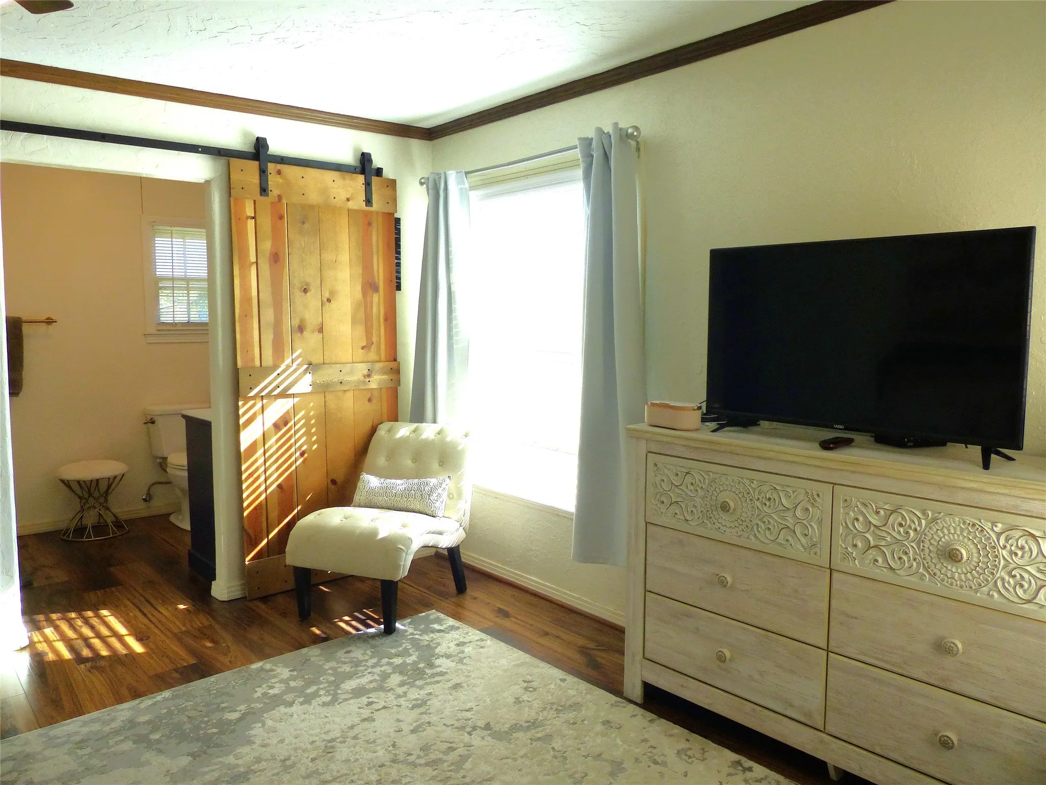 Sitting room featuring dark wood-style floors, crown molding, a barn door, and a textured ceiling