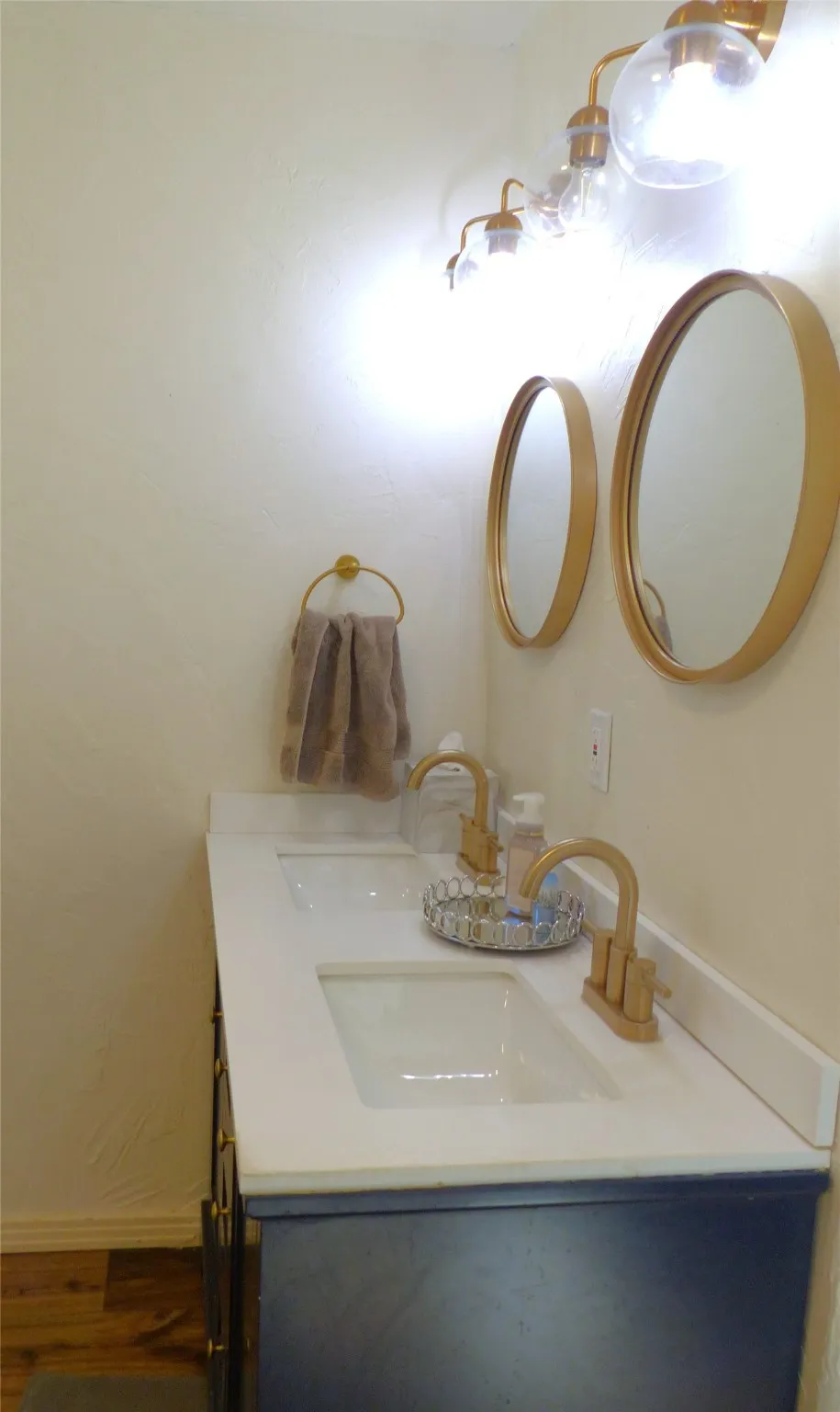 Full bath featuring double vanity and dark wood-type flooring