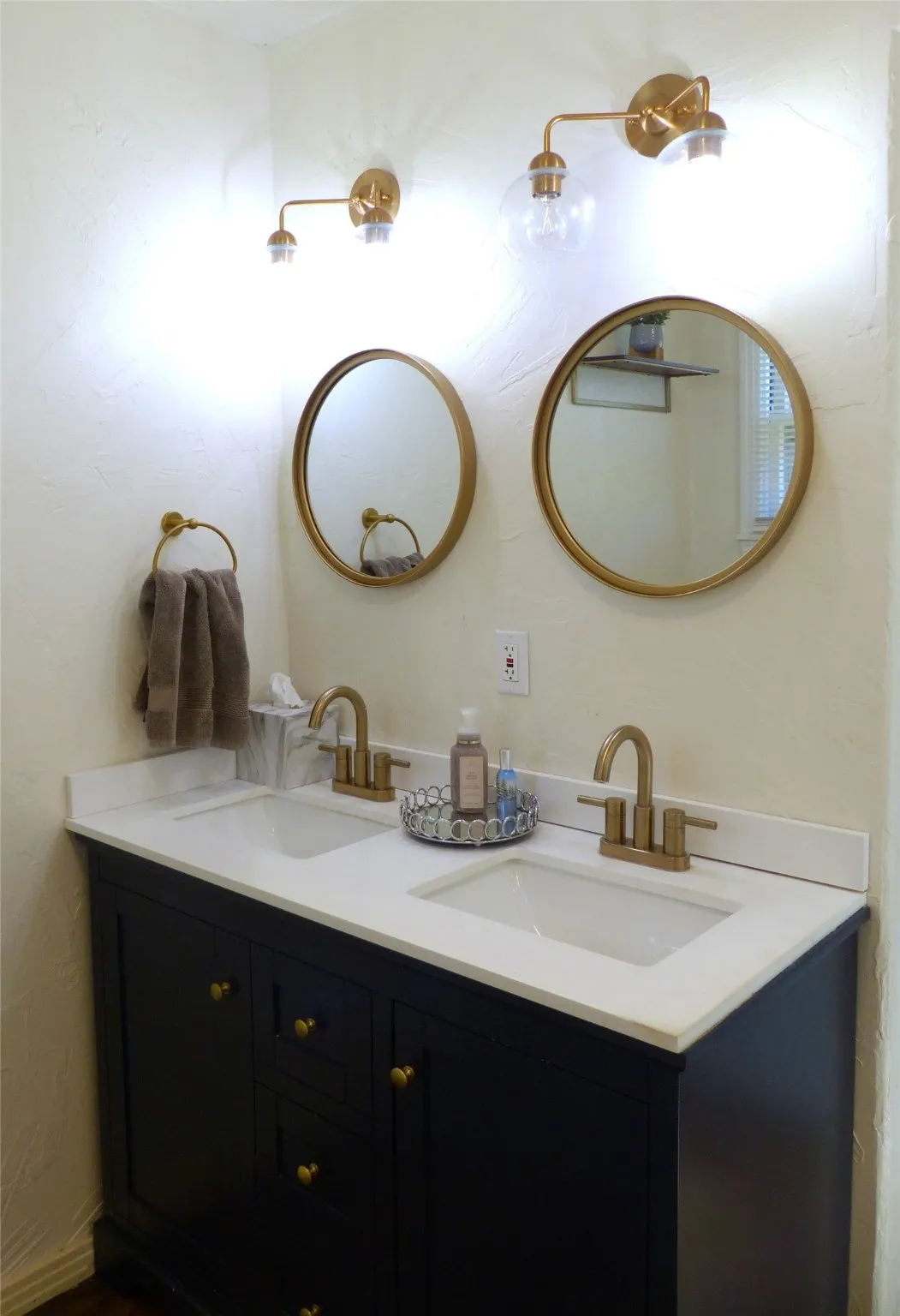 Full bathroom with double vanity and a textured wall
