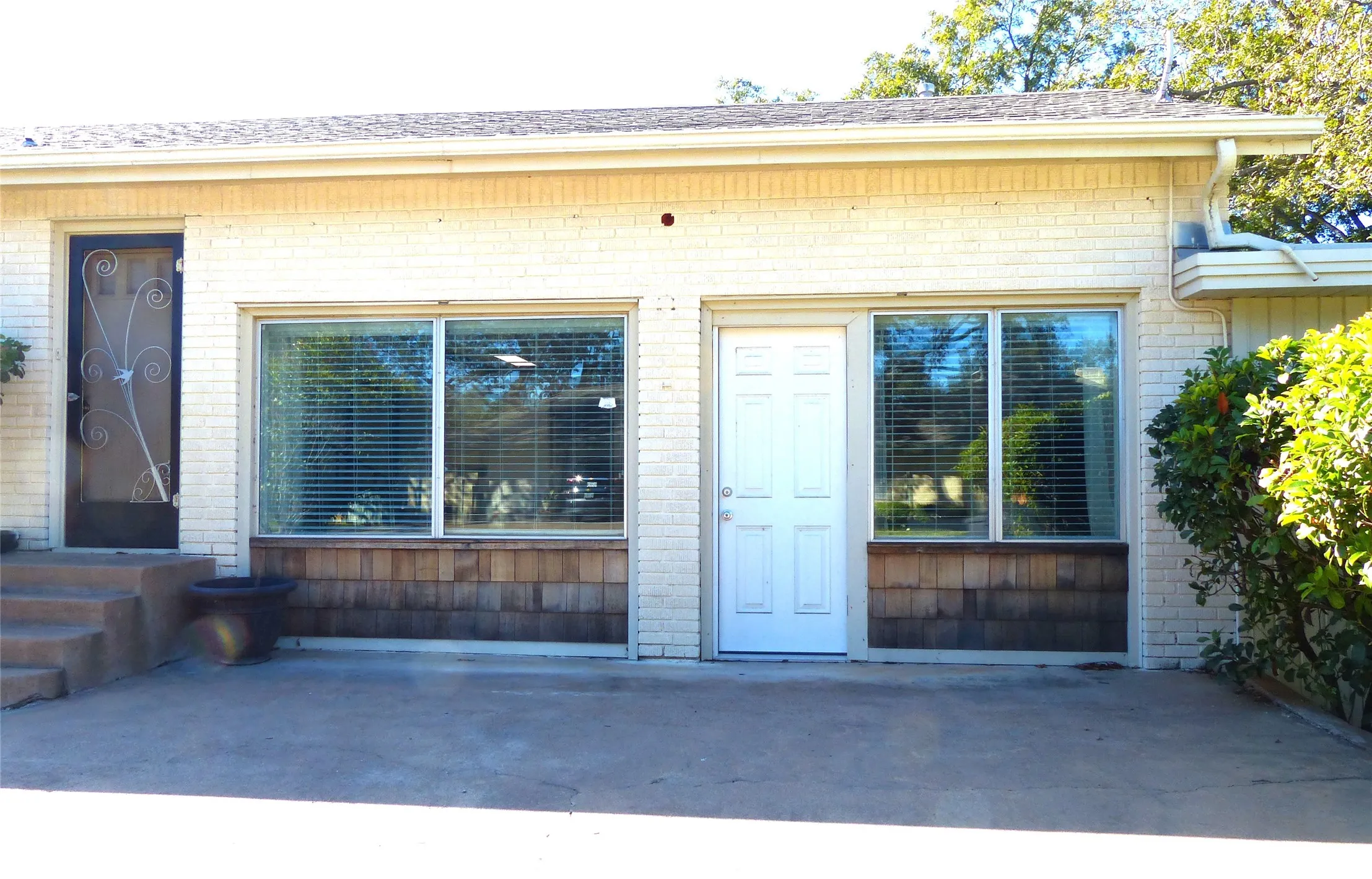 Doorway to property with brick siding and a shingled roof