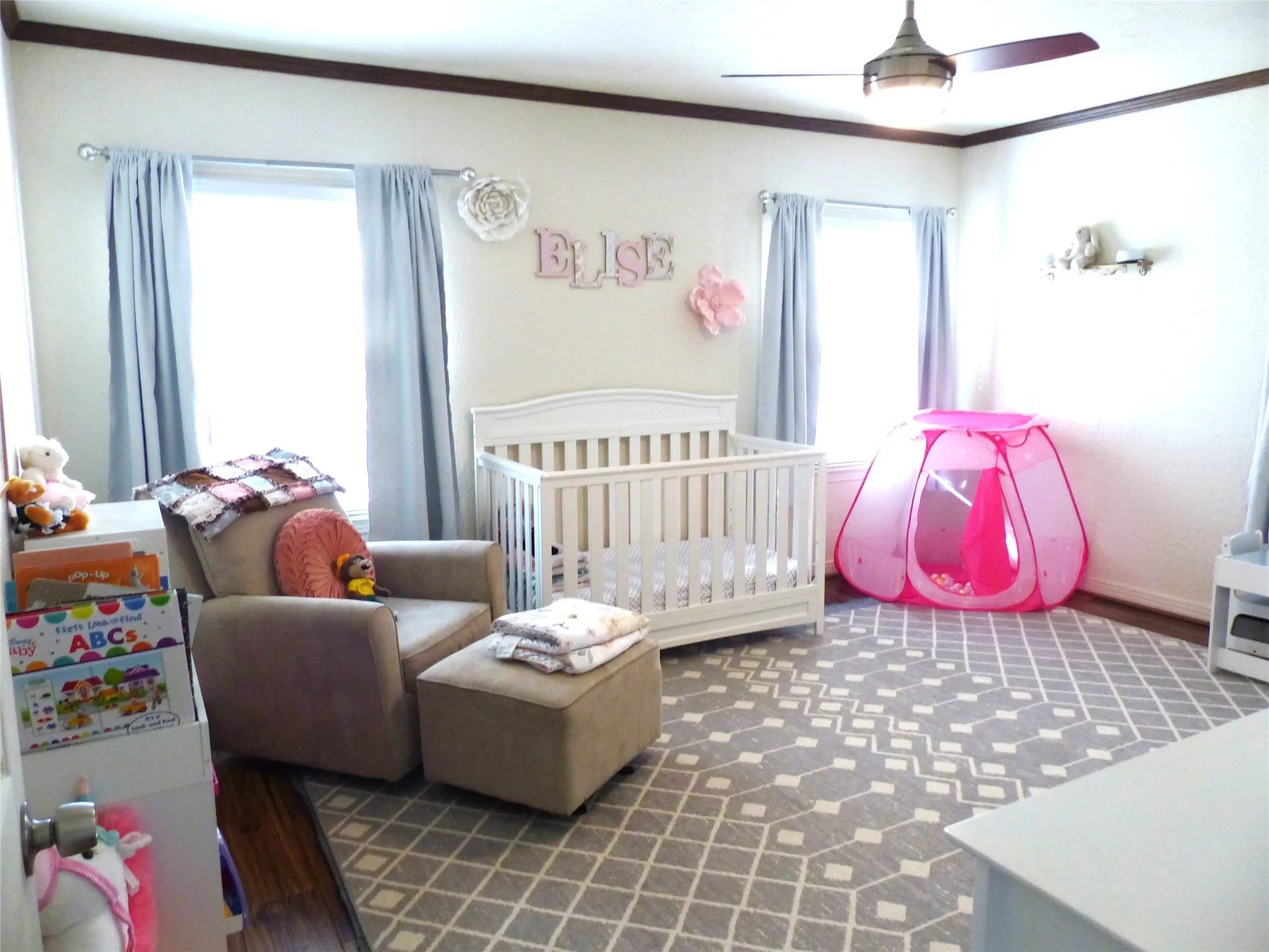 Bedroom featuring ornamental molding, a crib, ceiling fan, and dark wood finished floors