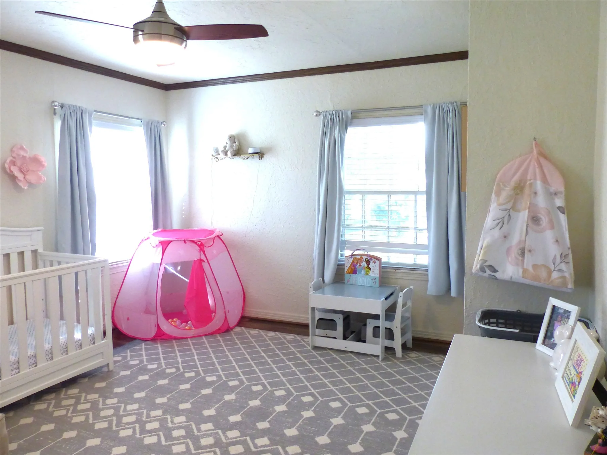 Bedroom with a crib, crown molding, a textured wall, and ceiling fan