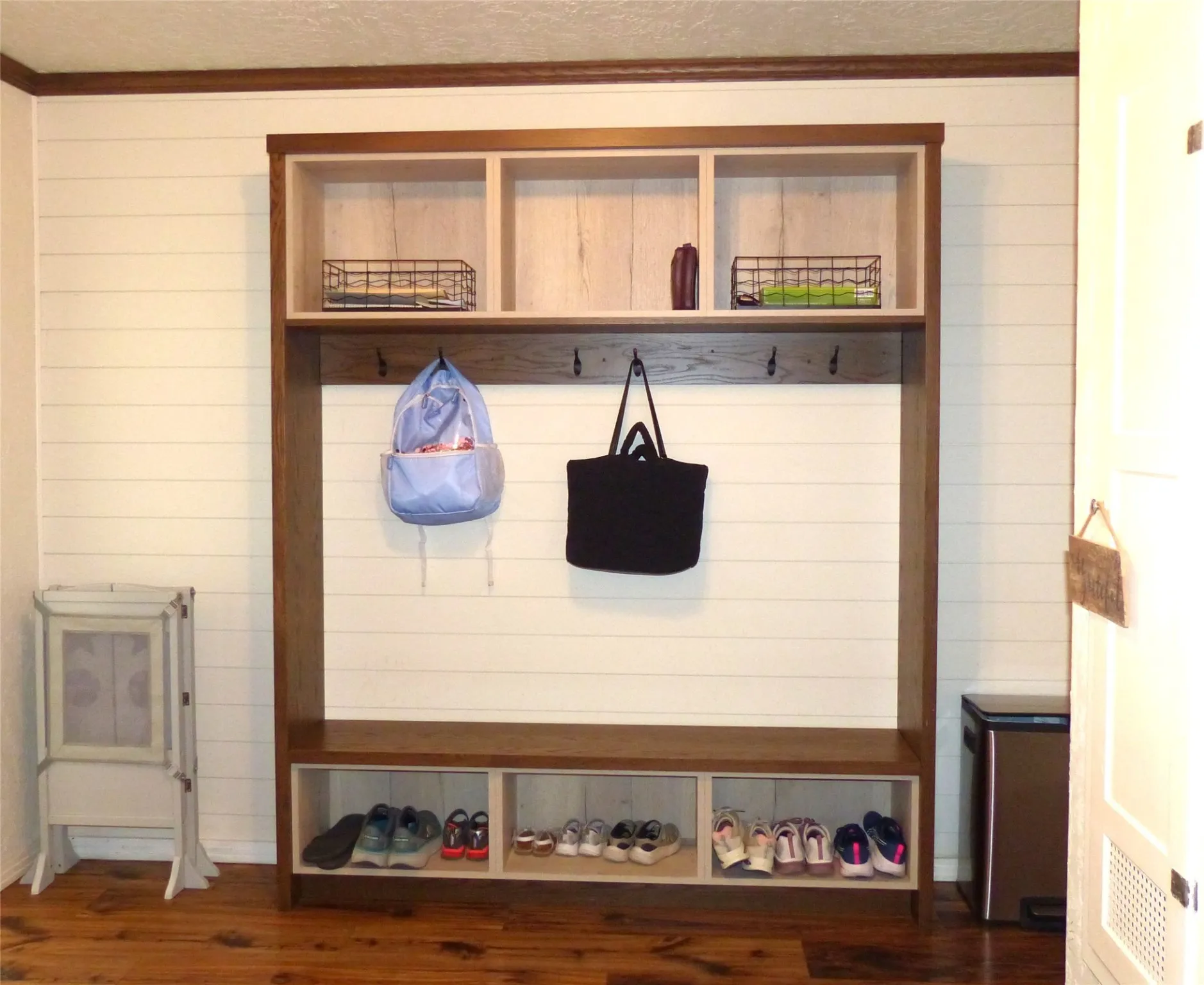 Mudroom featuring dark wood-style flooring, wood walls, ornamental molding, and a textured ceiling