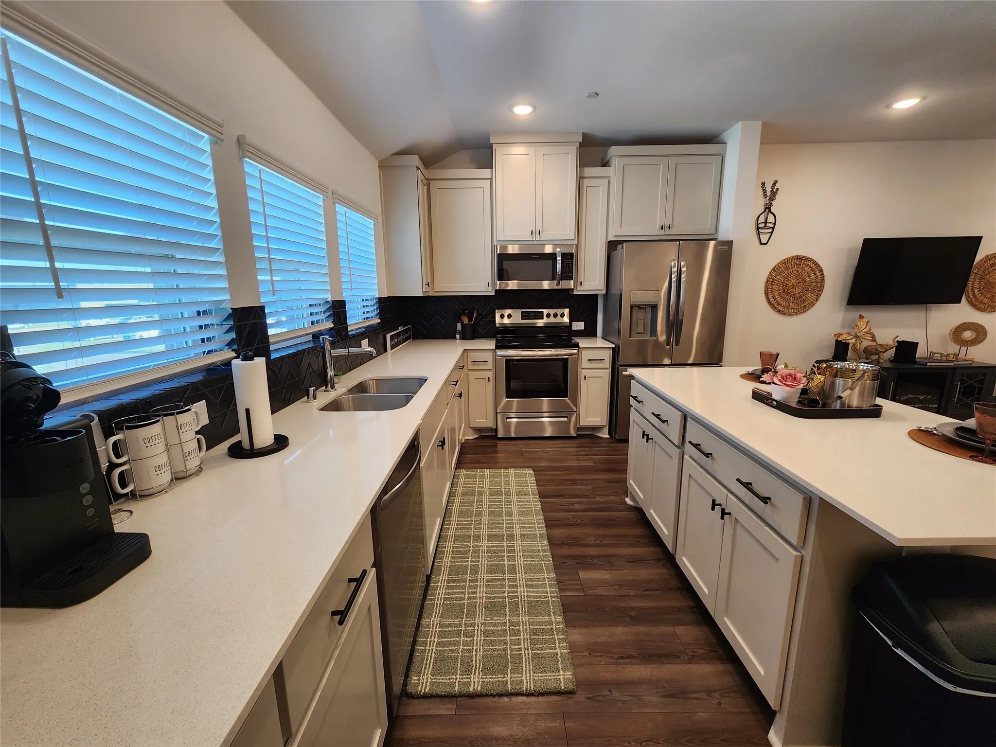 Kitchen featuring tasteful backsplash, appliances with stainless steel finishes, dark wood finished floors, lofted ceiling, and white cabinets
