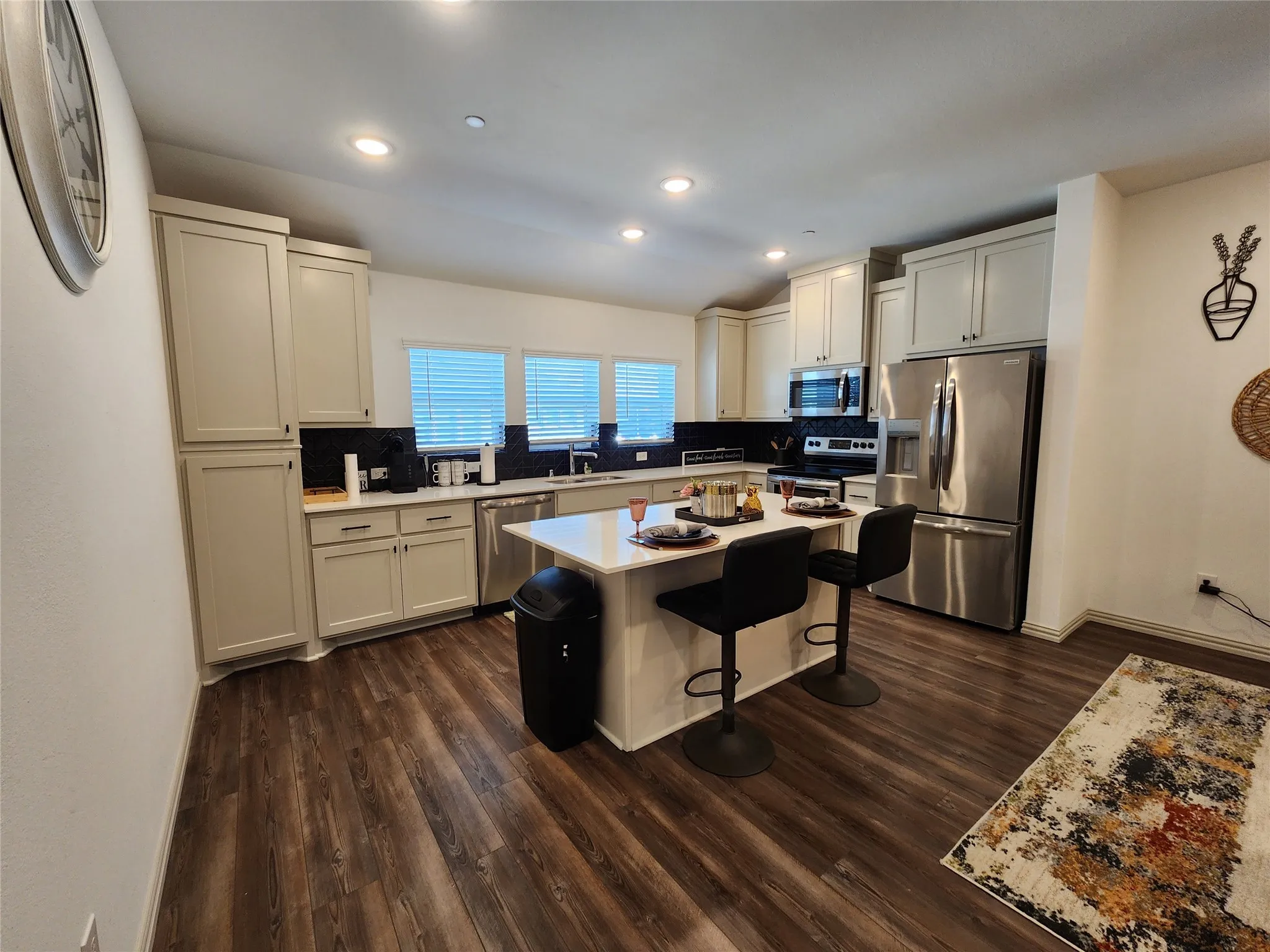 Kitchen featuring backsplash, stainless steel appliances, a center island, dark wood-type flooring, and recessed lighting