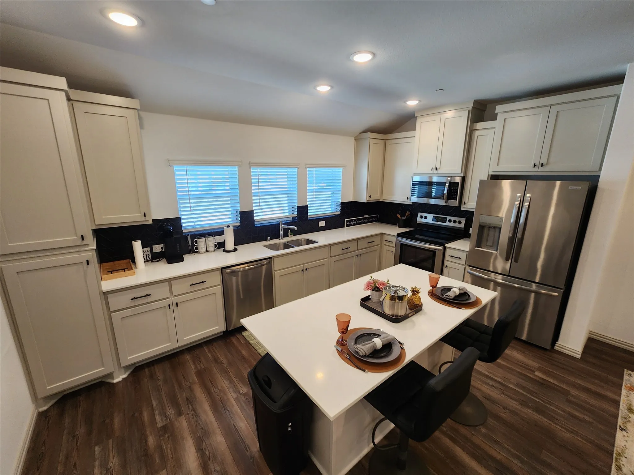 Kitchen with decorative backsplash, stainless steel appliances, recessed lighting, a breakfast bar, and dark wood finished floors