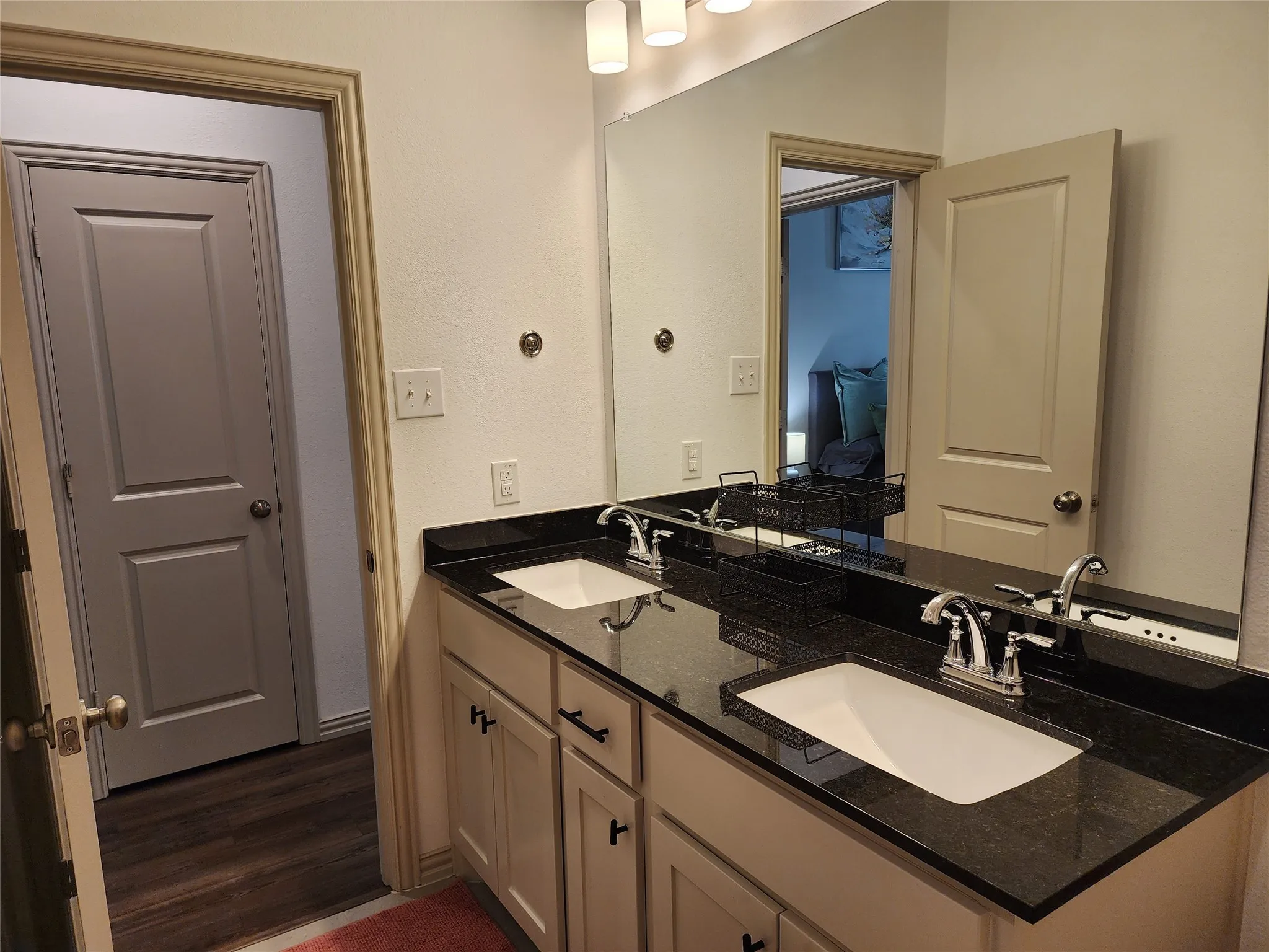 Full bath with double vanity and dark wood-style flooring