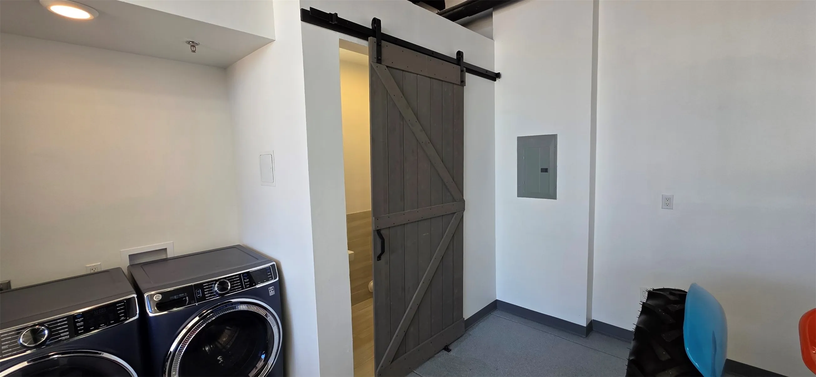 Laundry area featuring a barn door, independent washer and dryer, electric panel, and recessed lighting