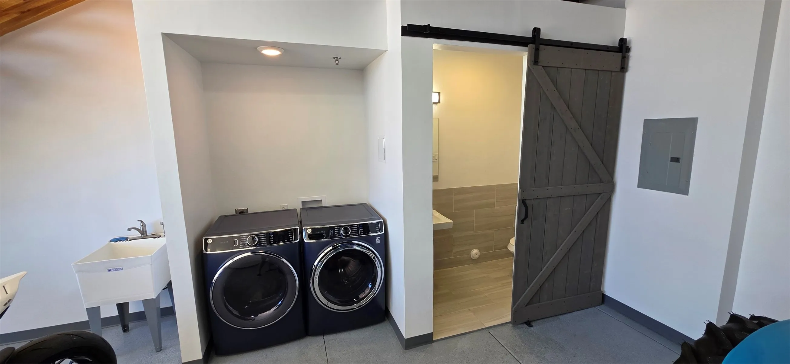 Laundry area with a barn door, electric panel, and washing machine and clothes dryer