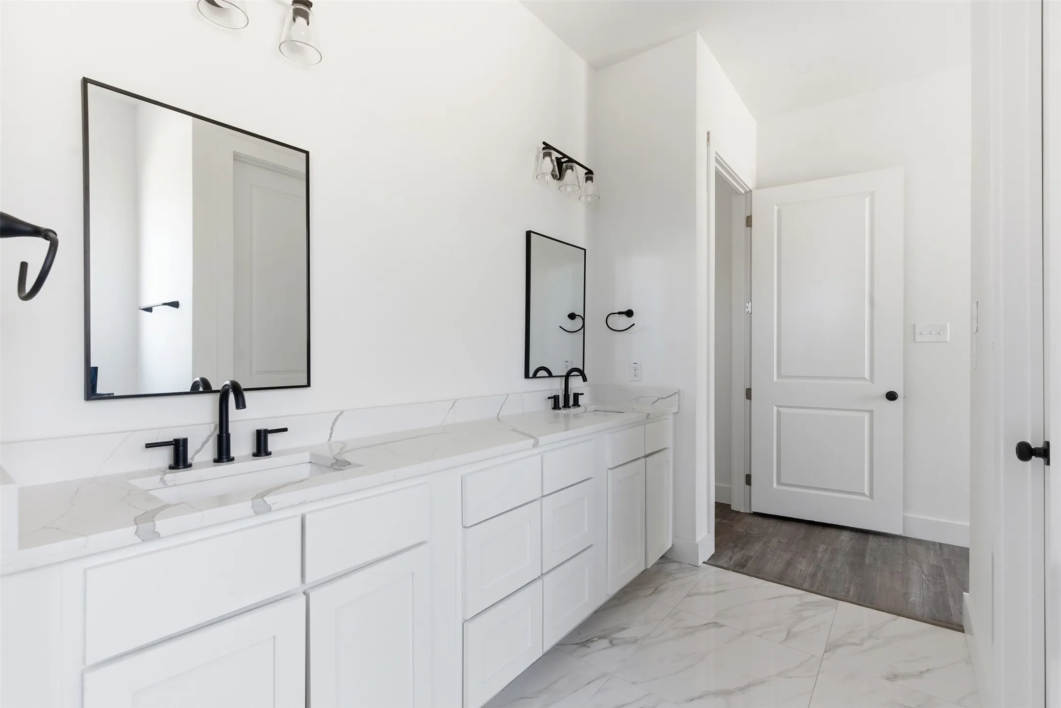 Bathroom with double vanity and light marble finish floors