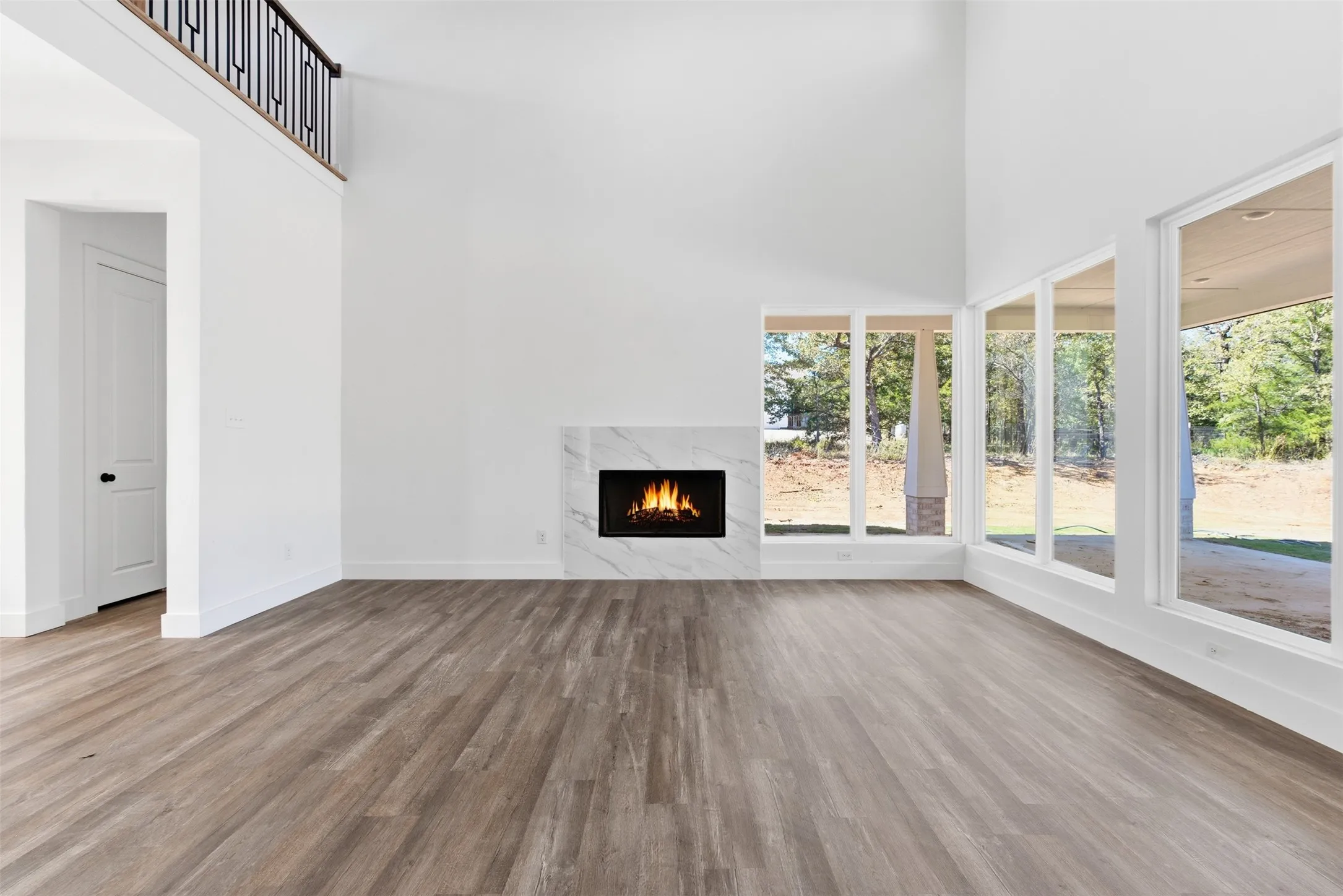 Unfurnished living room featuring a towering ceiling, light wood-style flooring, and a fireplace