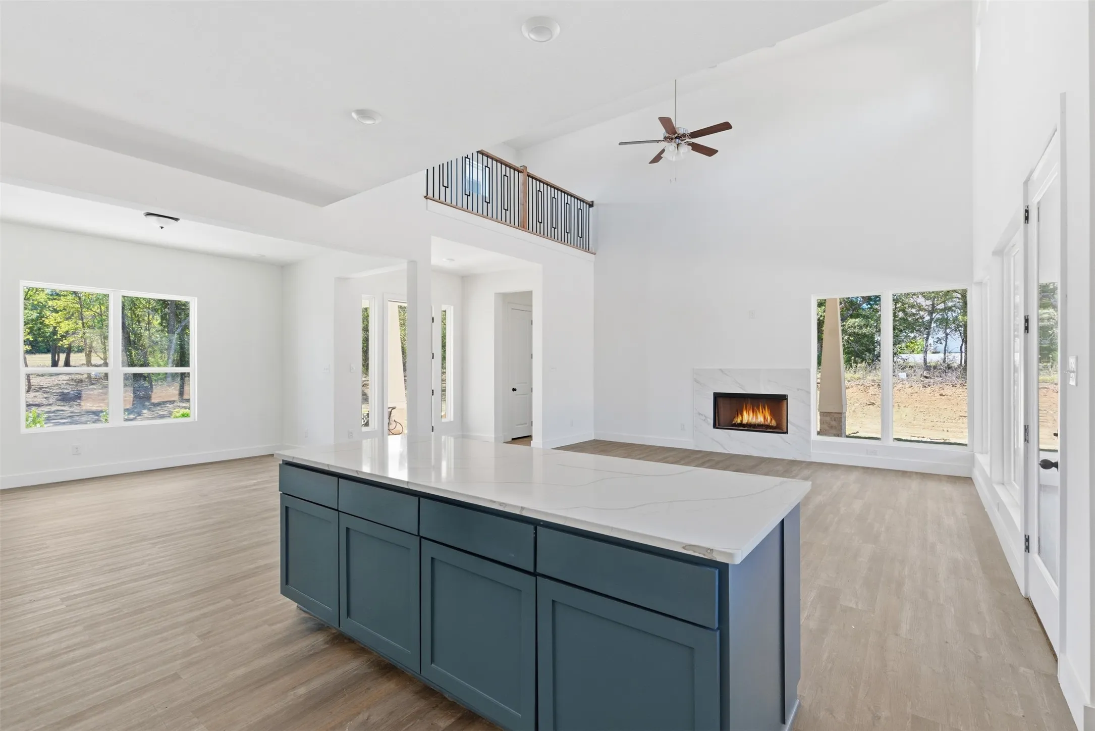 Kitchen with blue cabinetry, open floor plan, a high end fireplace, light wood finished floors, and a high ceiling