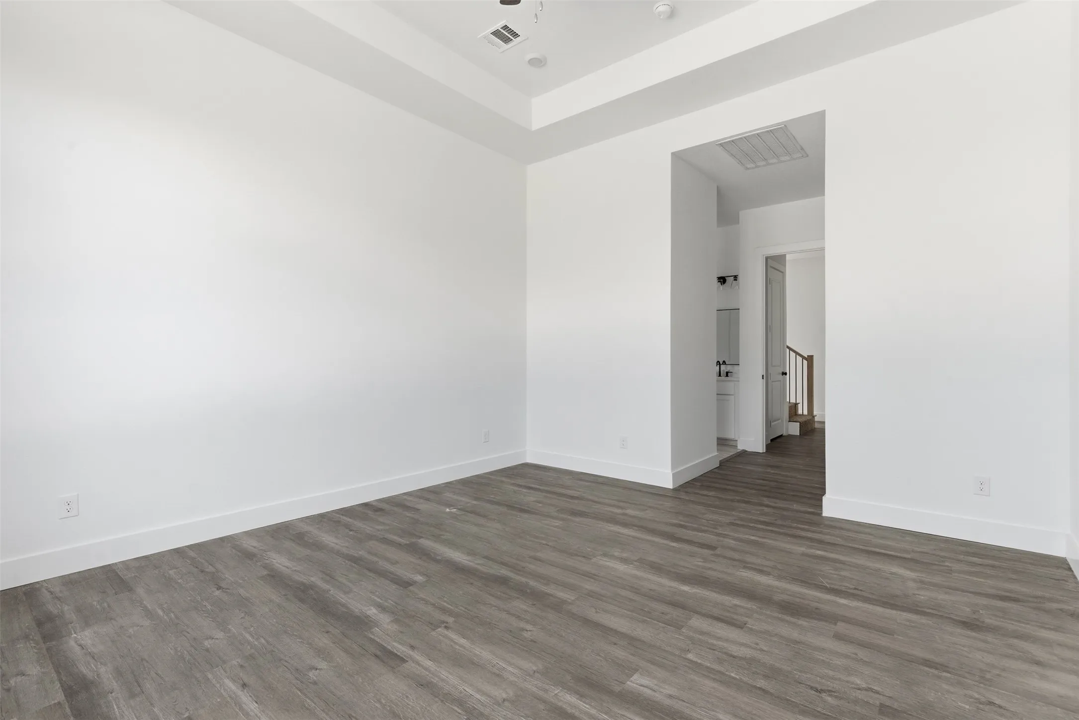 Unfurnished room featuring wood finished floors and a tray ceiling