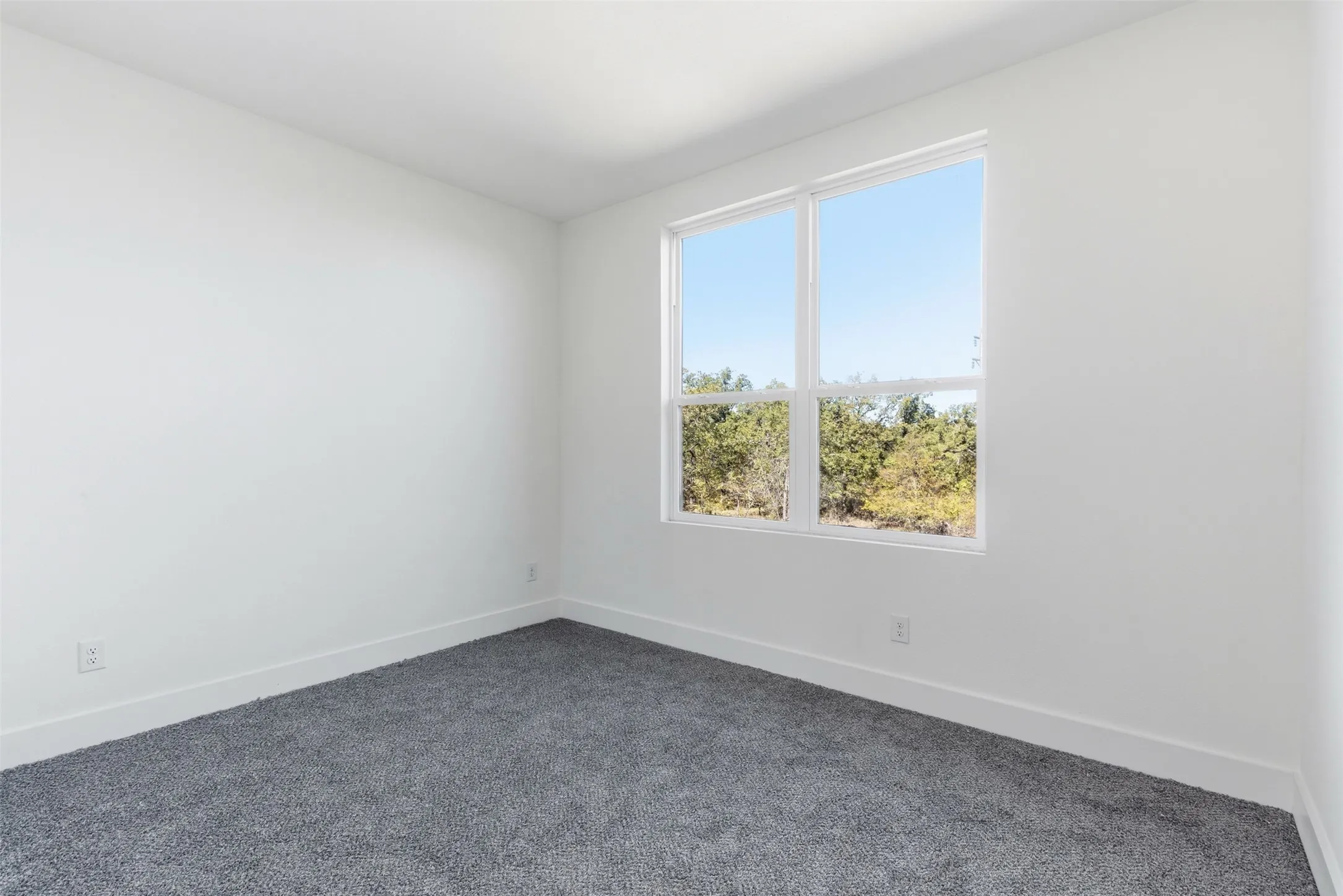 Unfurnished room with baseboards and dark carpet