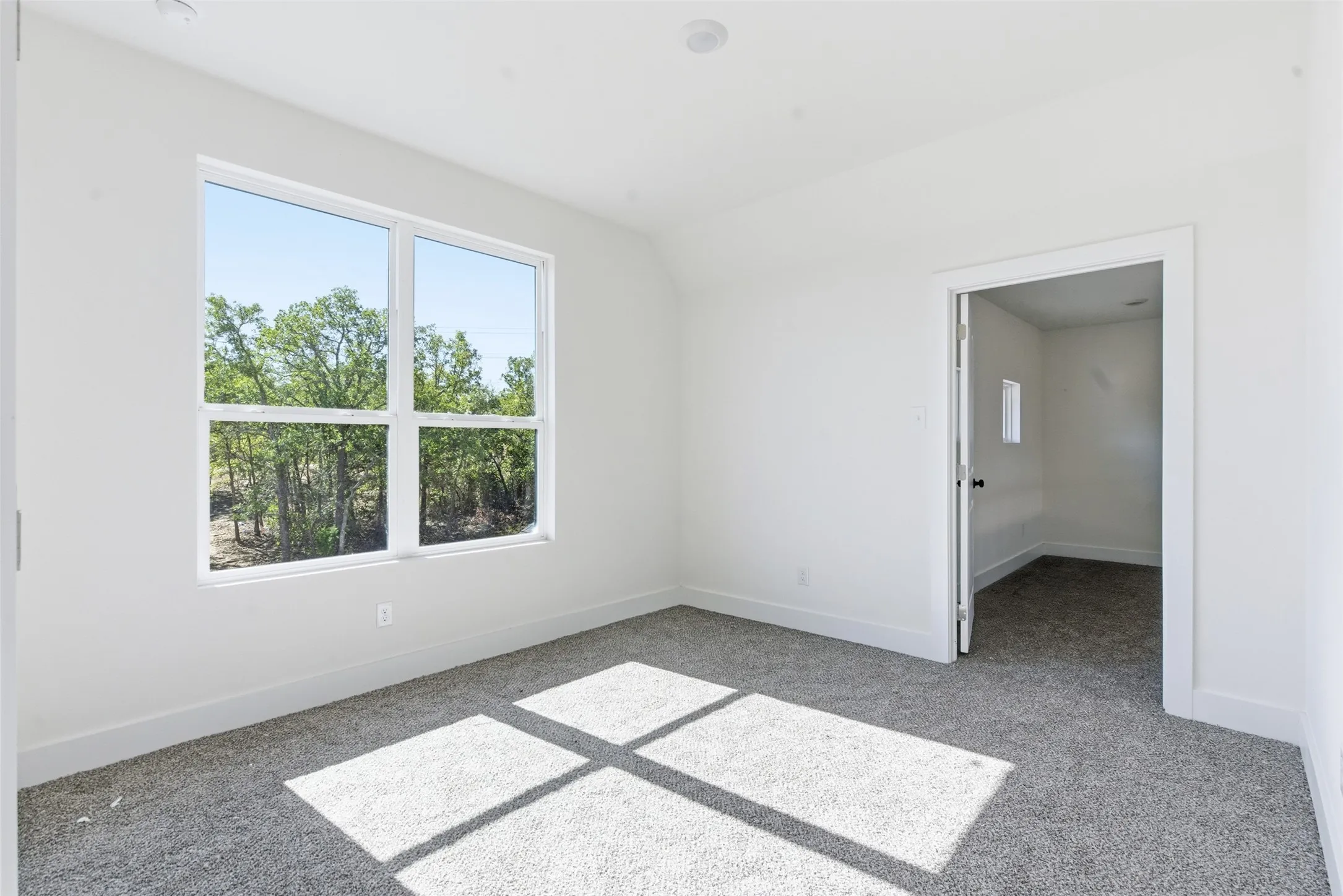 Unfurnished room with light carpet and lofted ceiling