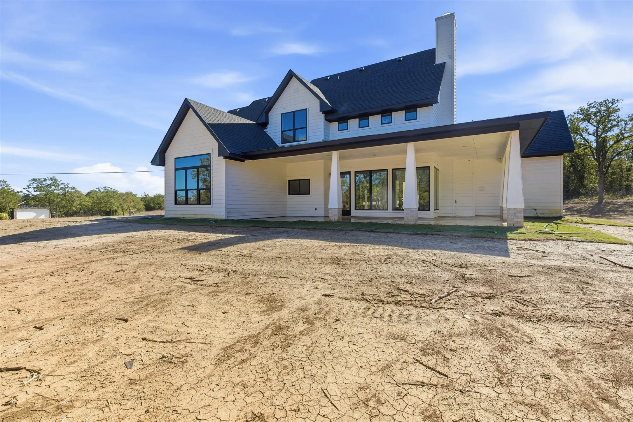 View of front of property featuring a patio, roof with shingles, and a chimney