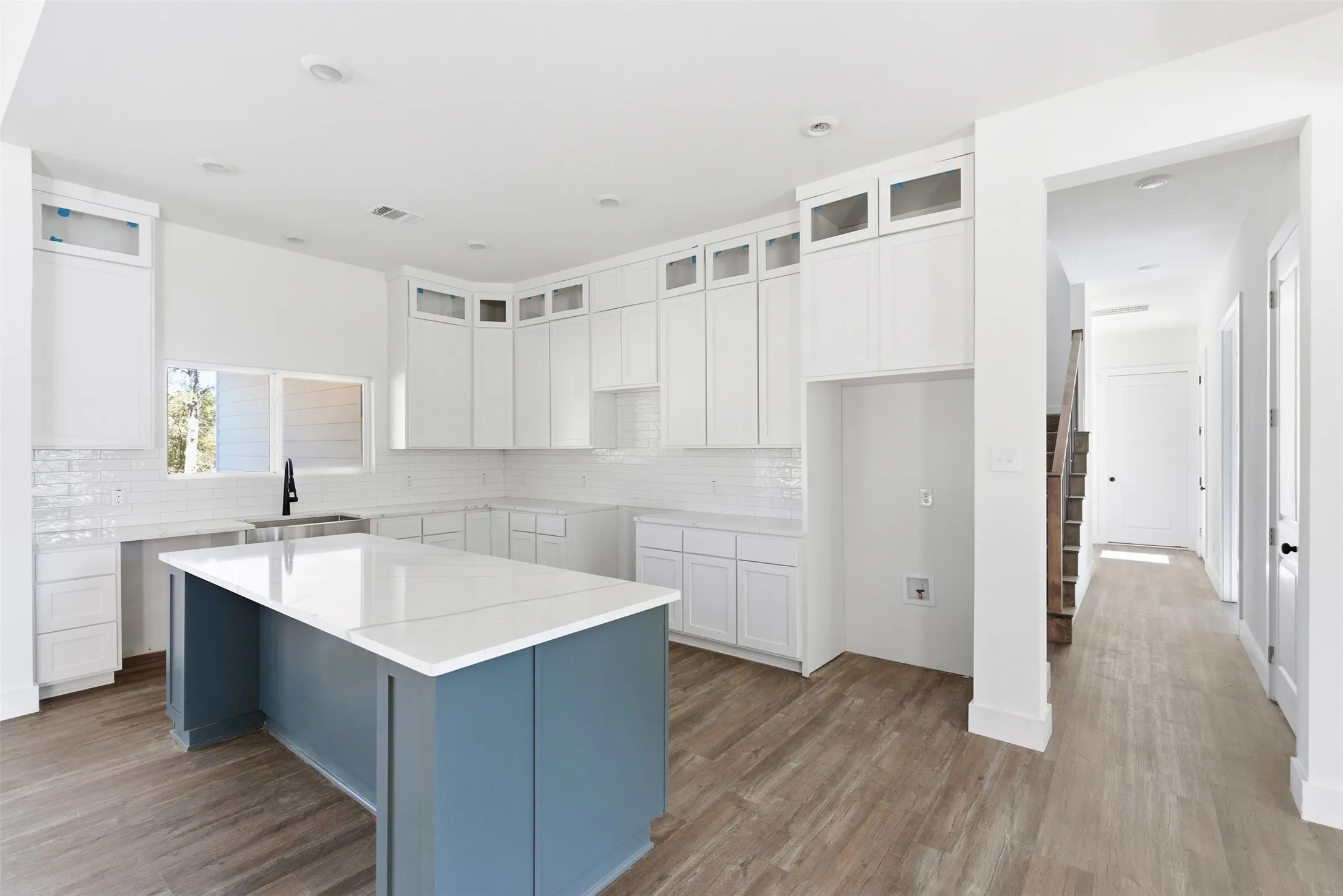 Kitchen with white cabinets, a kitchen island, wood finished floors, and backsplash