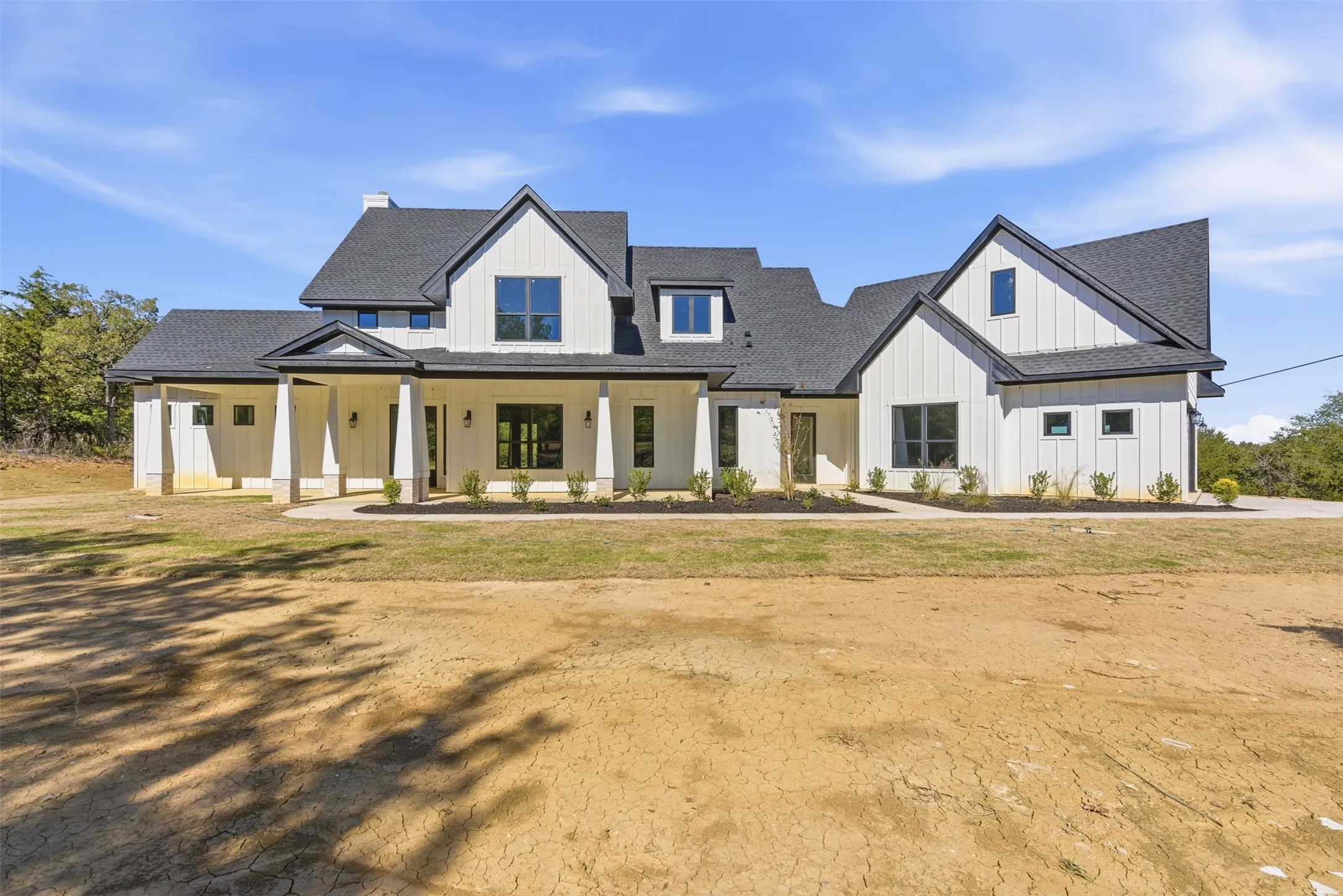 Modern inspired farmhouse featuring covered porch, roof with shingles, and board and batten siding