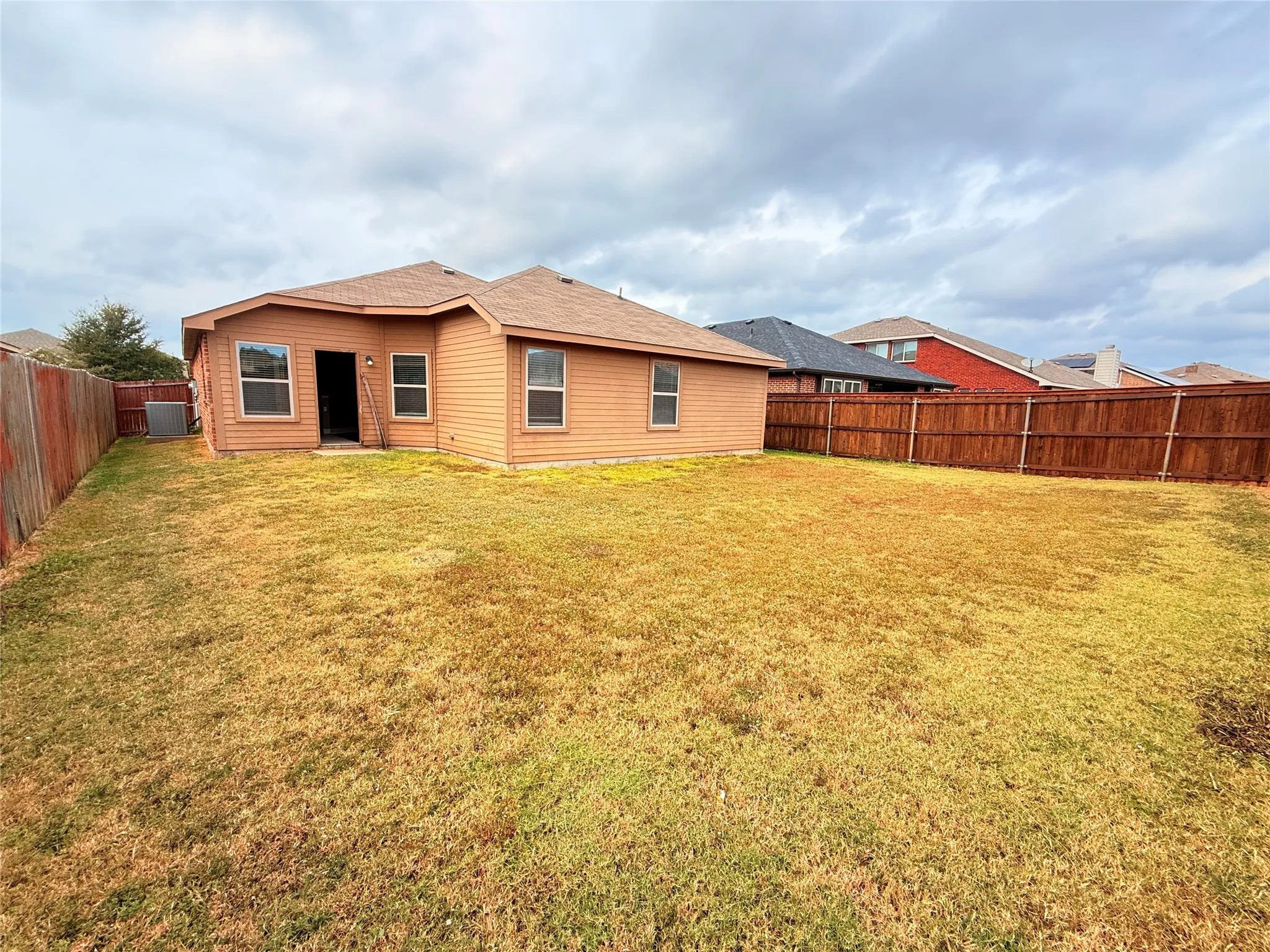 Rear view of property with a fenced backyard and roof with shingles