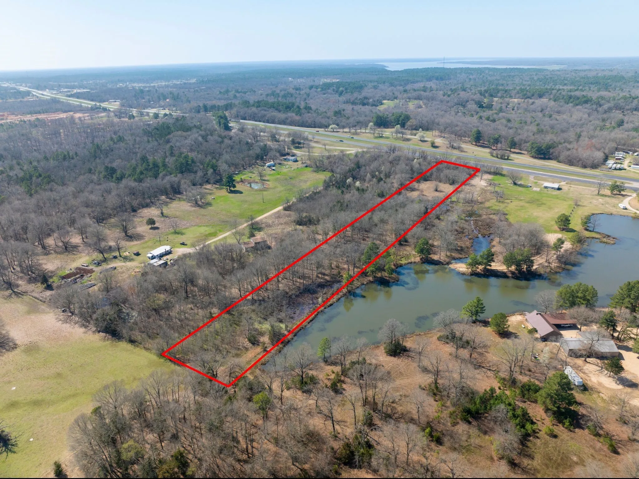 Aerial view of sparsely populated area featuring property boundaries highlighted and a large body of water