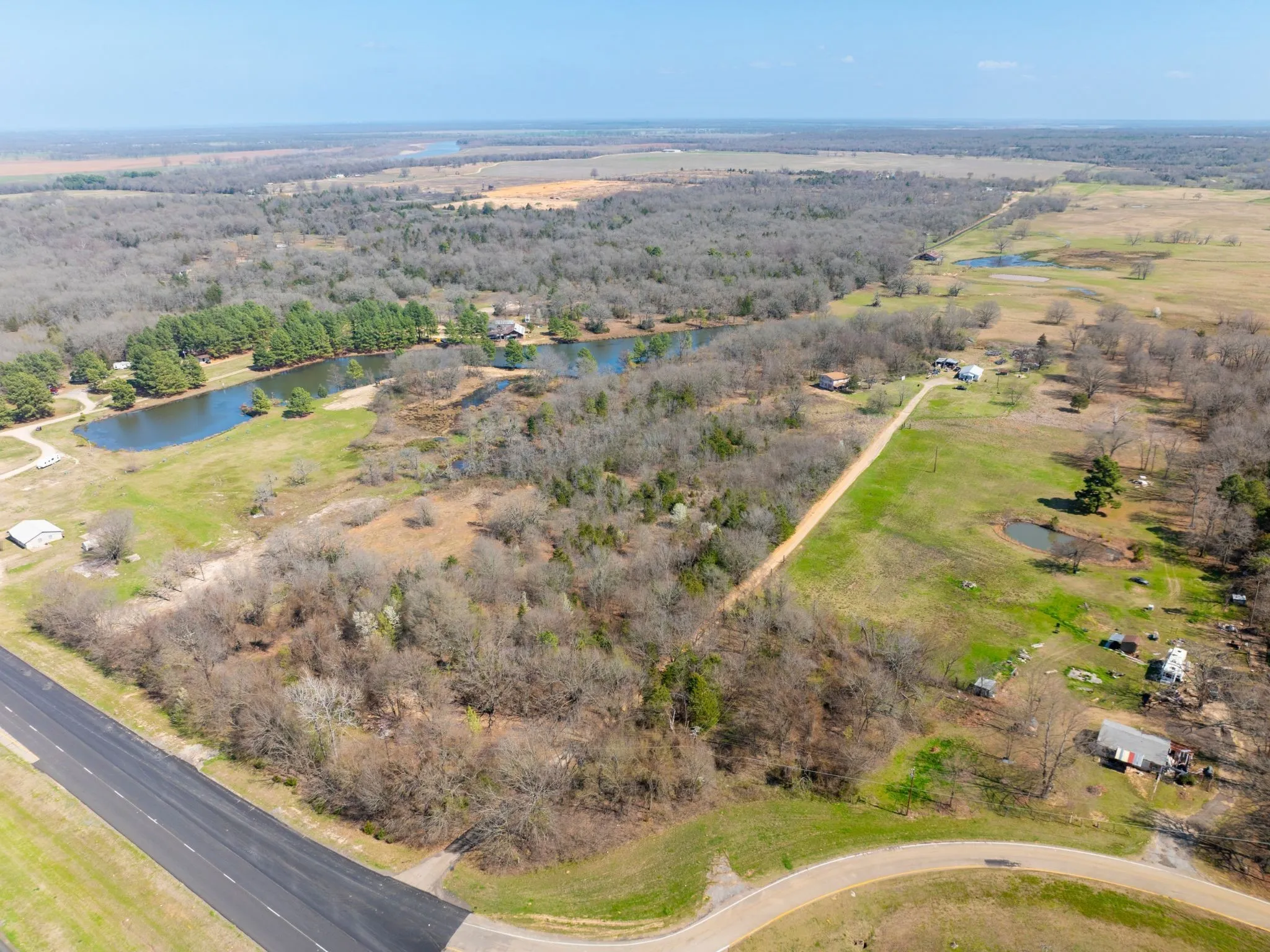 Aerial view of property and surrounding area featuring a large body of water and a heavily wooded area