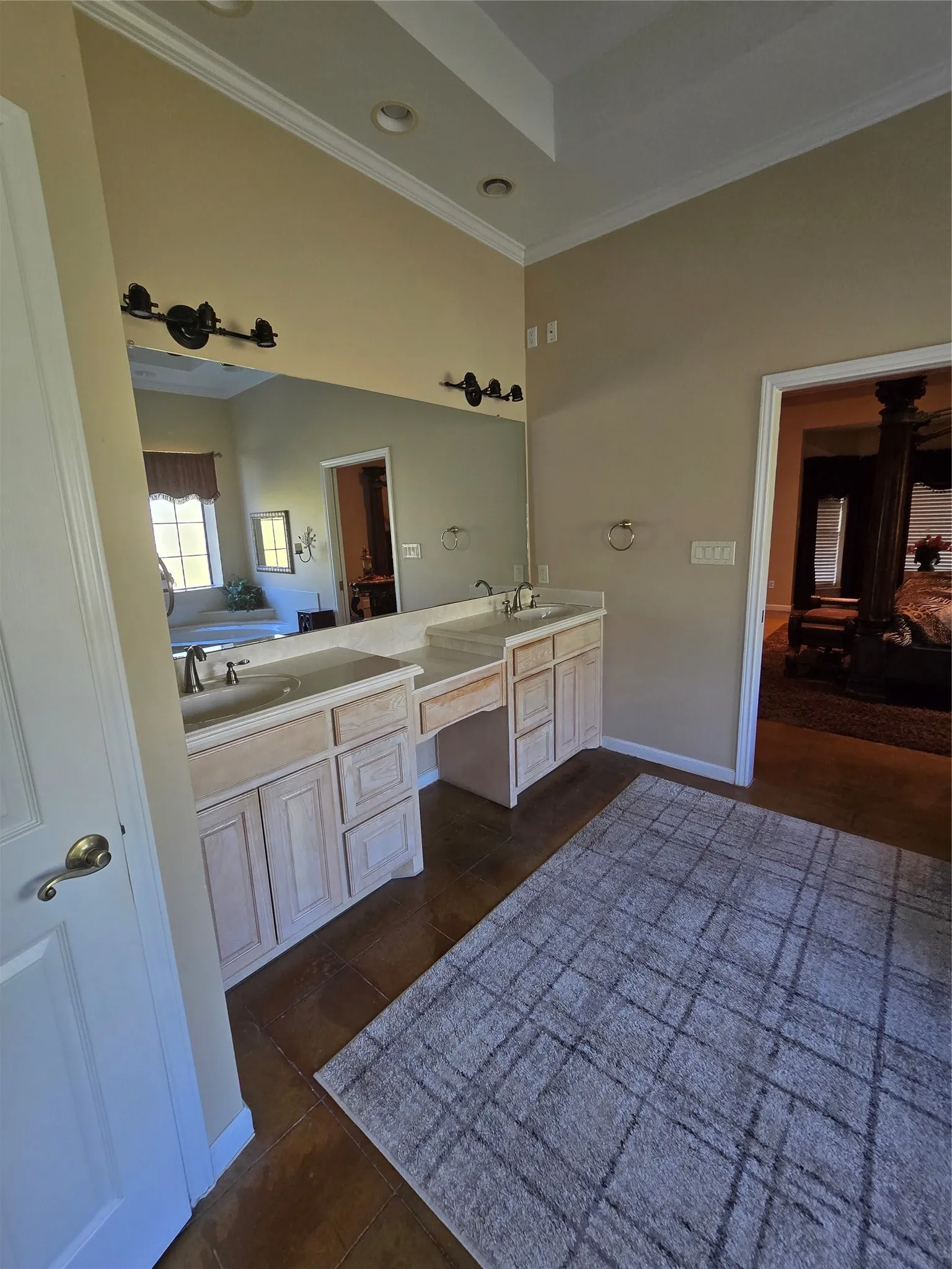 Ensuite bathroom featuring crown molding, double vanity, dark tile patterned floors, and recessed lighting