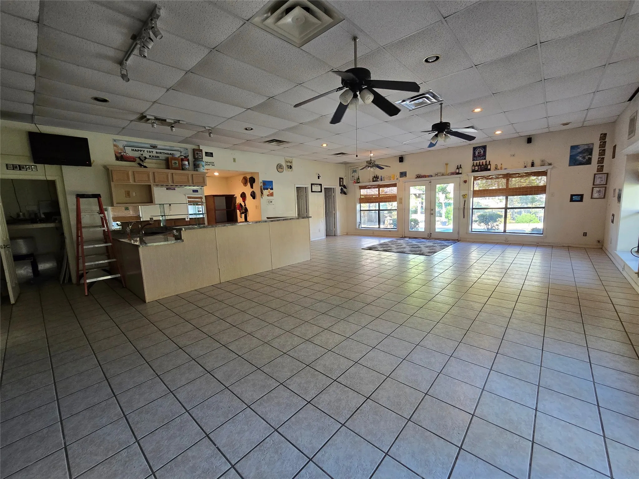Unfurnished living room with light tile patterned floors, a drop ceiling, french doors, a ceiling fan, and rail lighting
