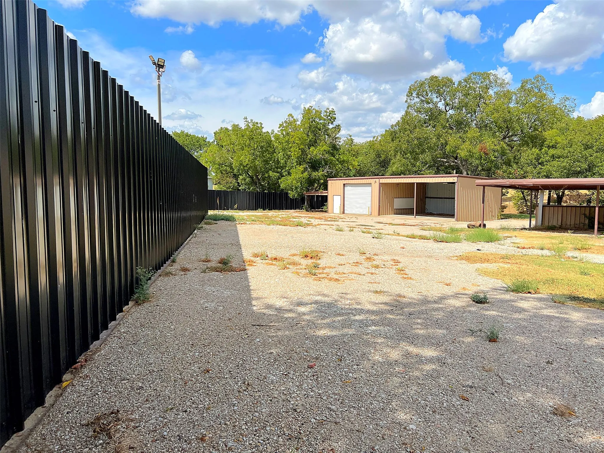 Black corrugated metal fencing along a gravel perimeter