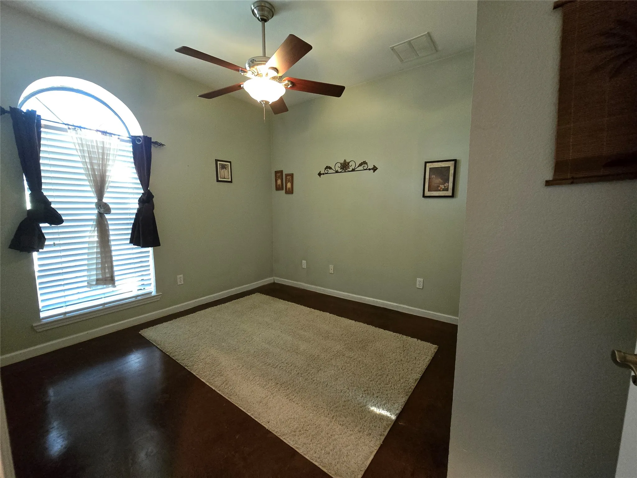 Empty room with a ceiling fan and dark wood-style flooring