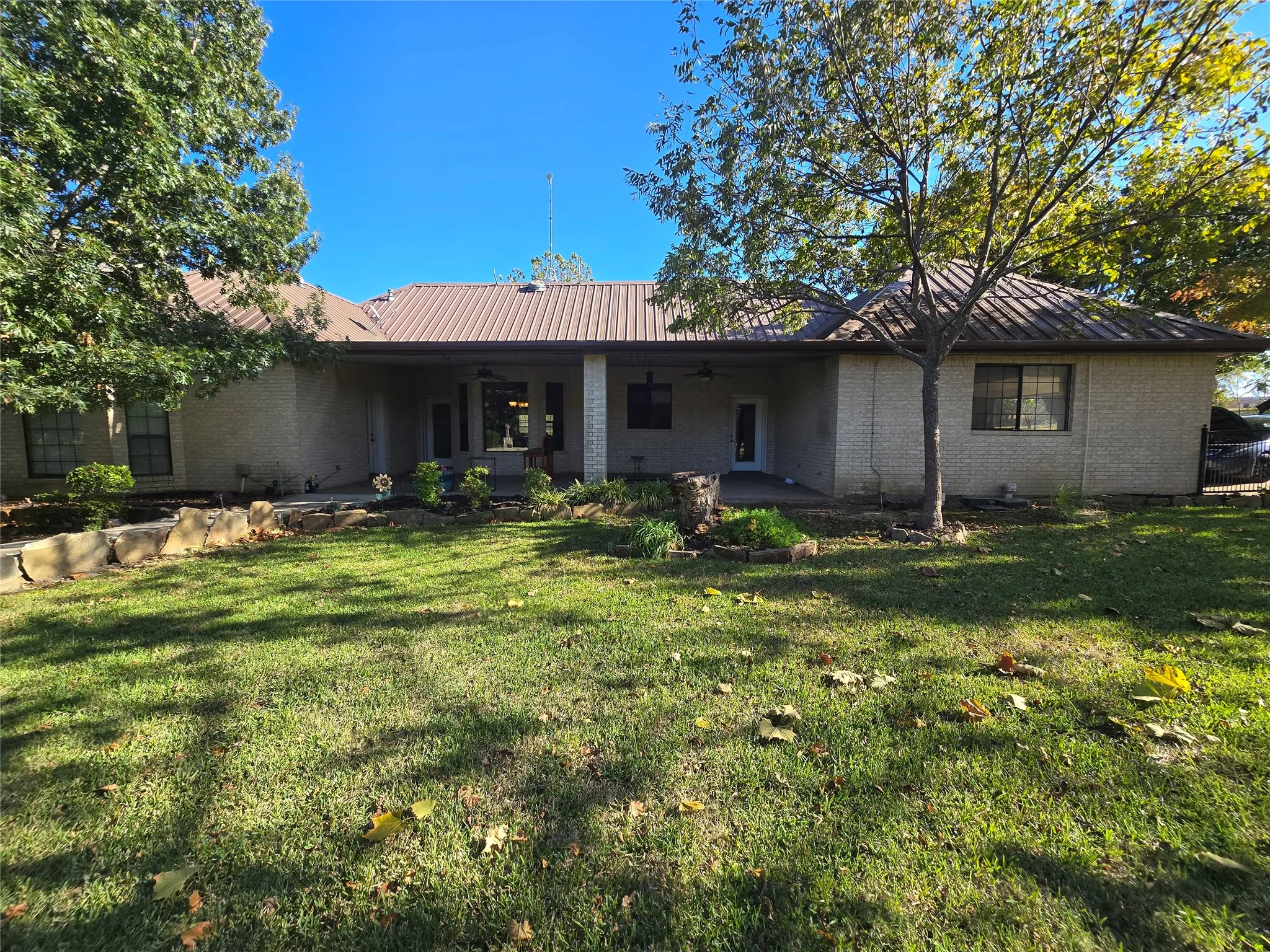 Rear view of house featuring a metal roof, ceiling fan, brick siding, and a patio